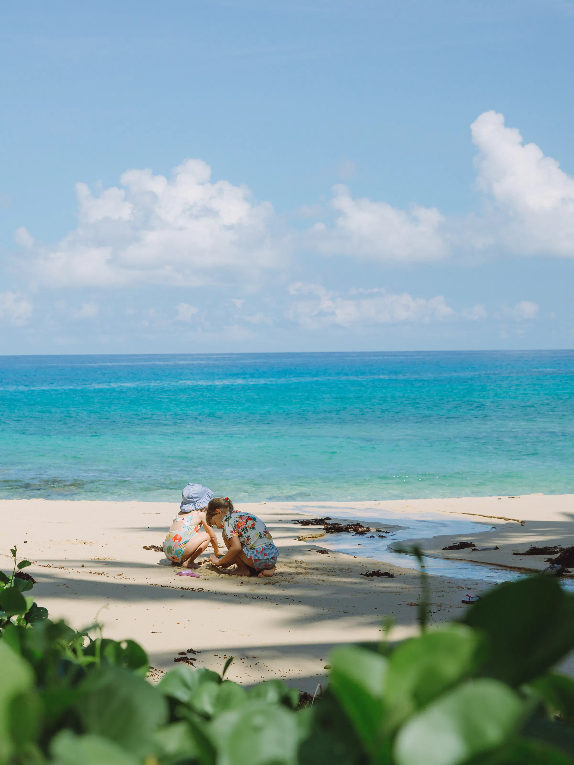 A sun lounger sits on a pristine white sand beach beside calm turquoise water in the Seychelles.