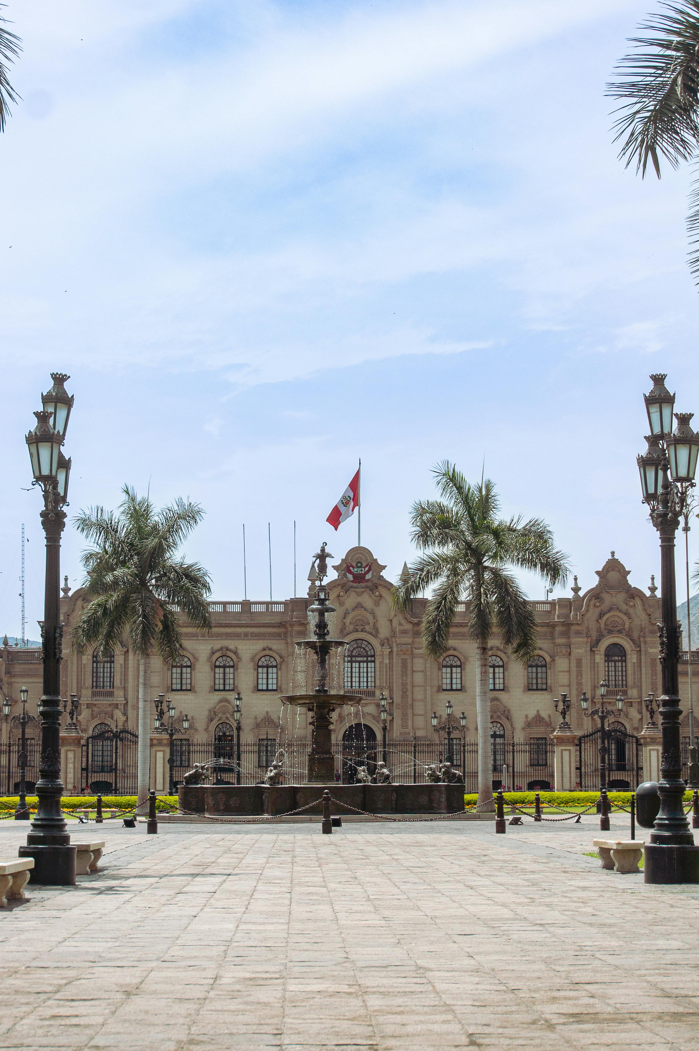 The ornate white colonial facade of the Government Palace faces Lima's Plaza Mayor at dusk.