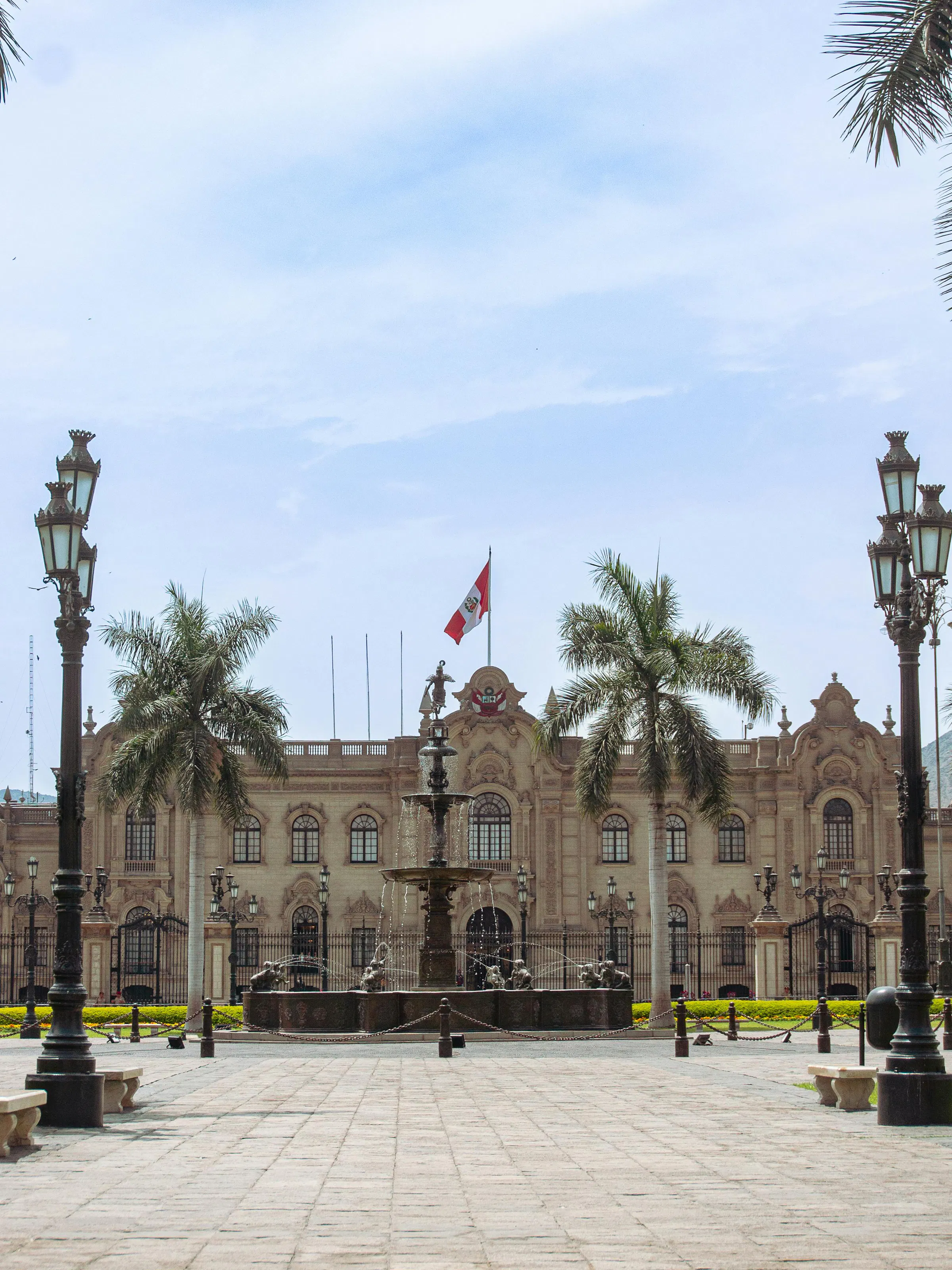 The ornate white colonial facade of the Government Palace faces Lima's Plaza Mayor at dusk.