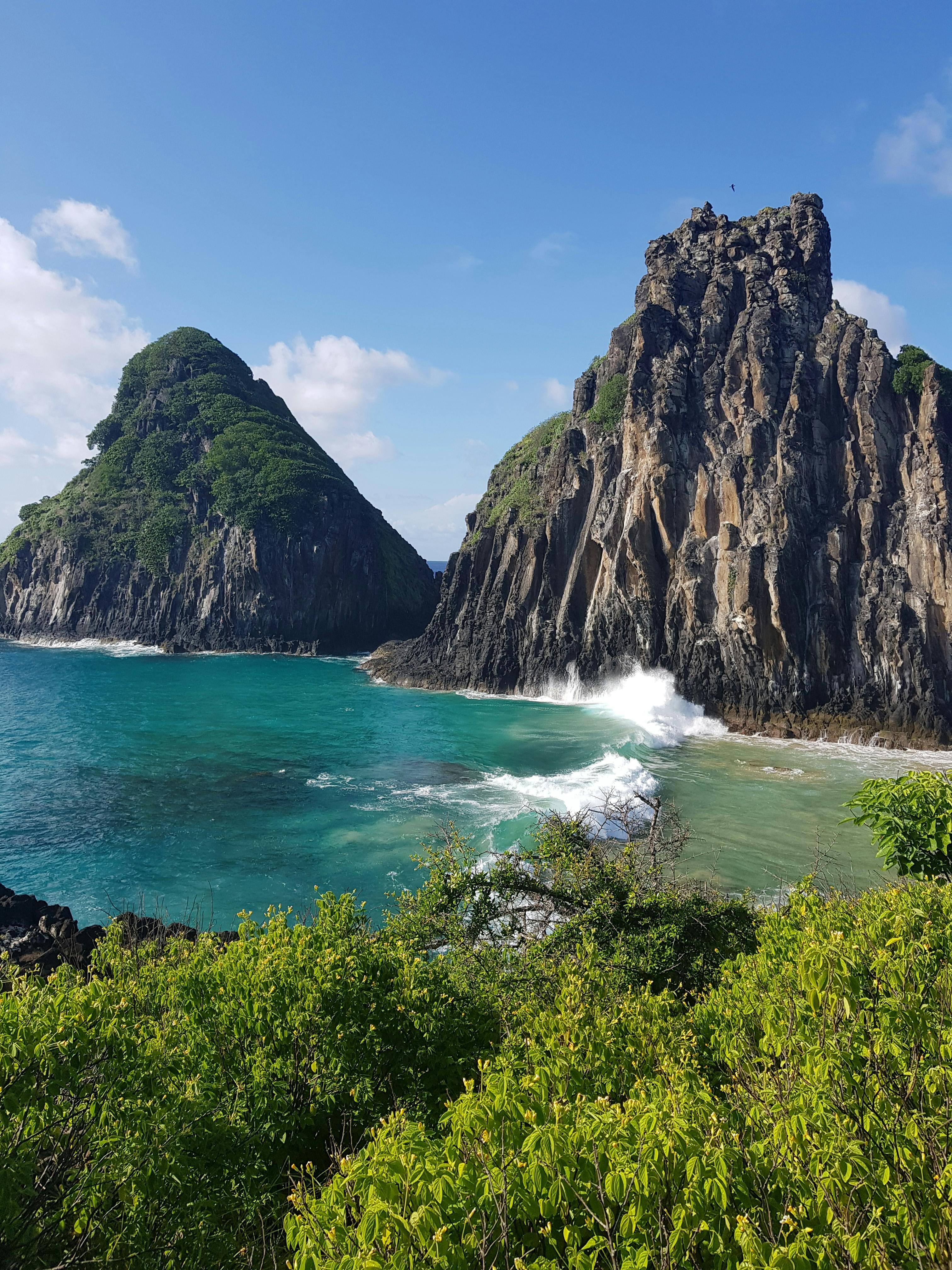 A dramatic twin-peaked volcanic rock formation rises from the ocean off Fernando de Noronha.