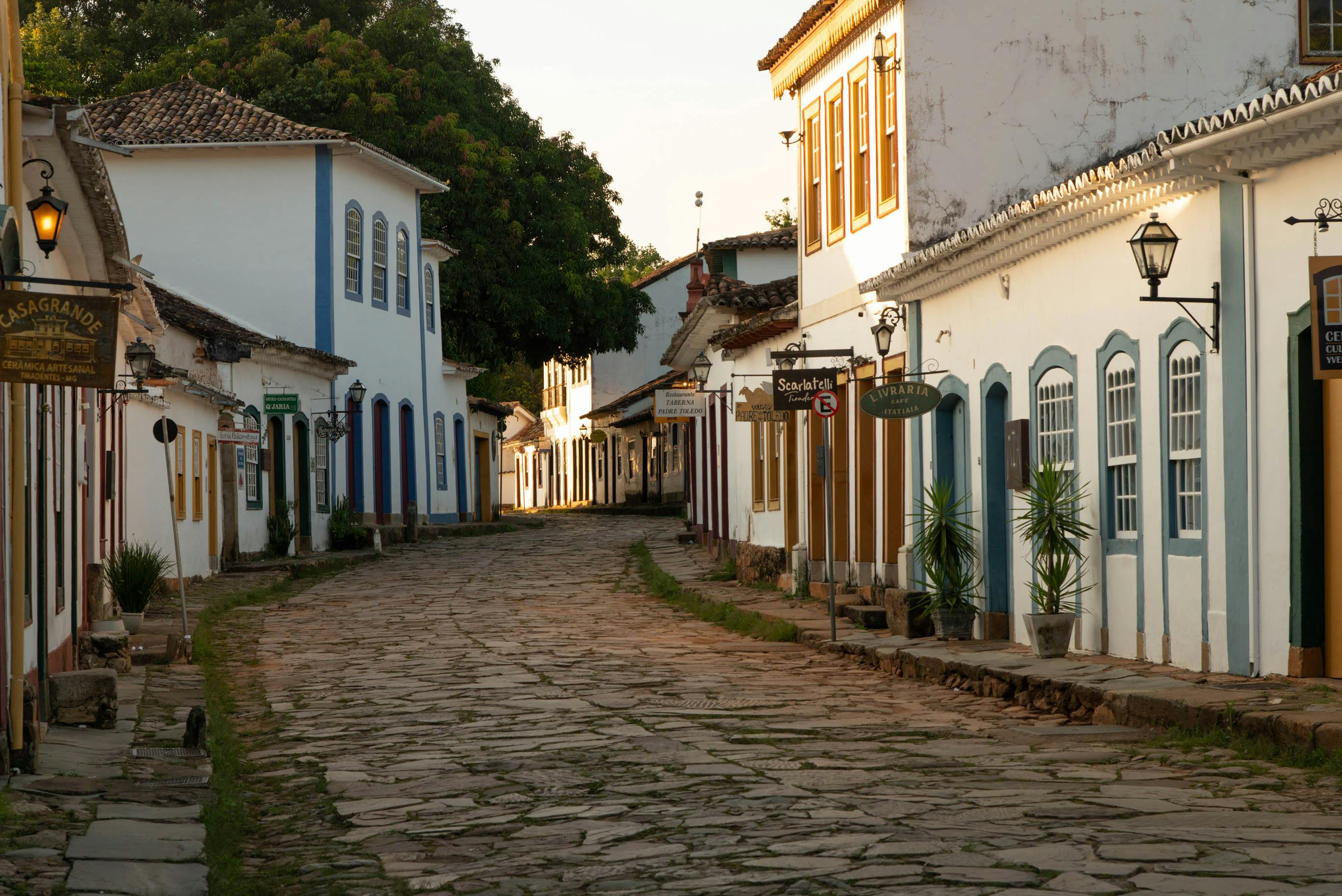 A quiet cobblestone street of white colonial buildings stretches through historic Paraty, Brazil.