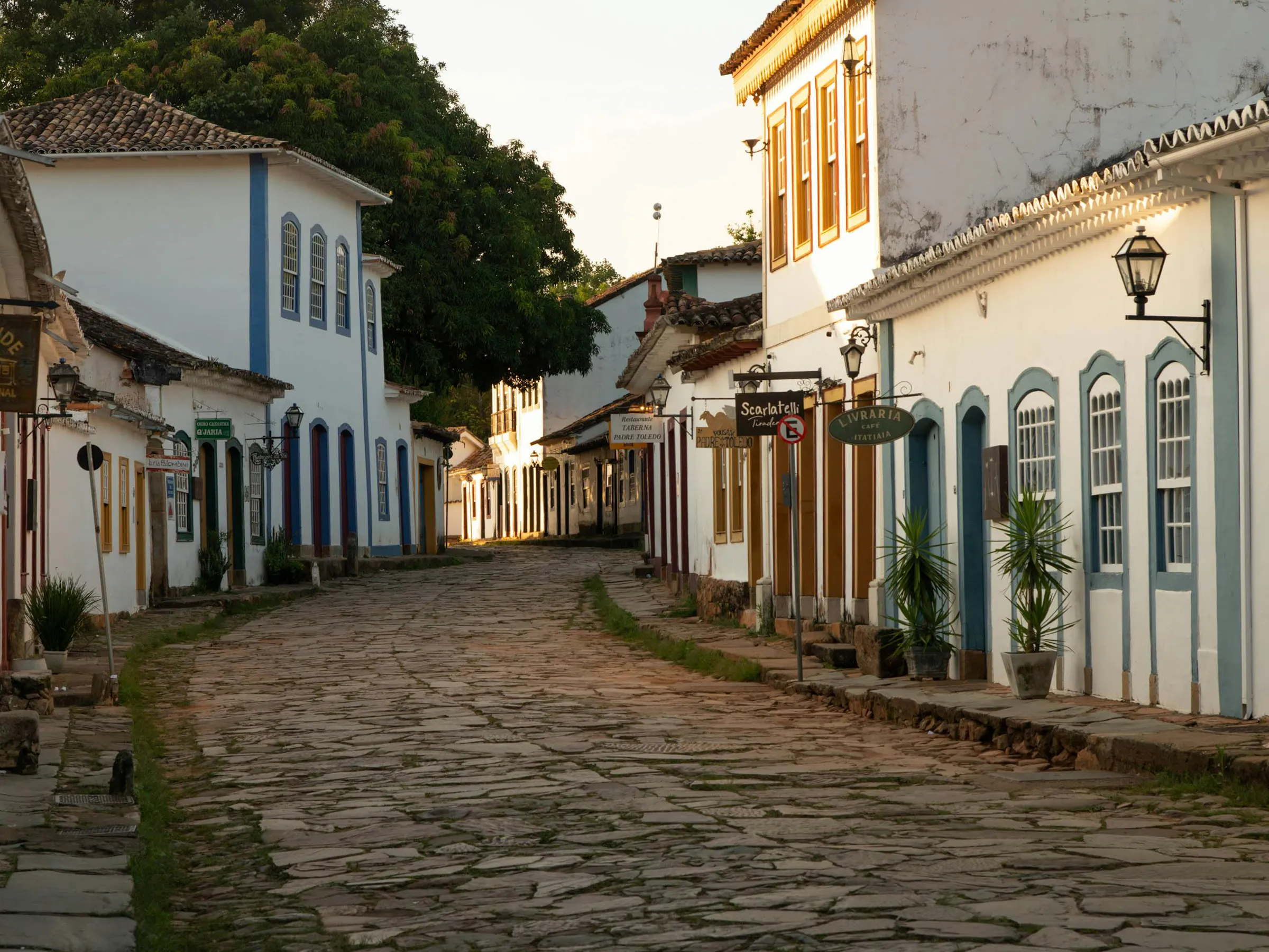 A quiet cobblestone street of white colonial buildings stretches through historic Paraty, Brazil.