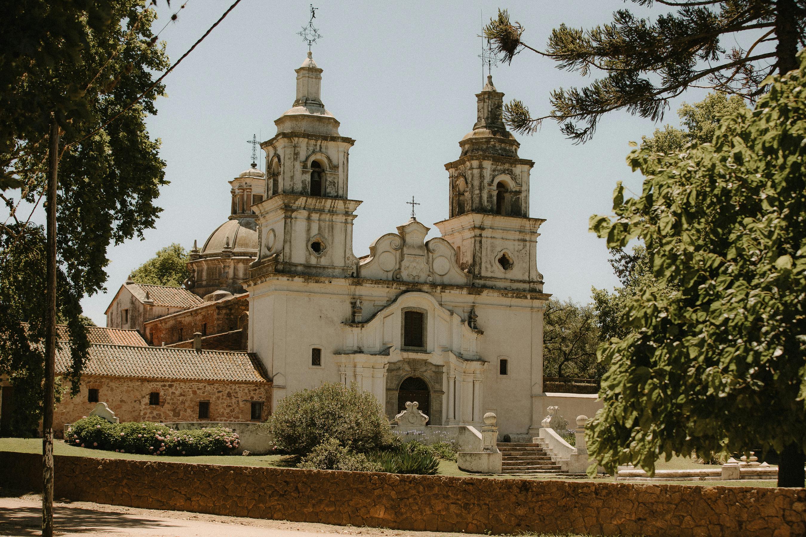 A colonial stone church with a bell tower stands in a wide square in Córdoba, Argentina.