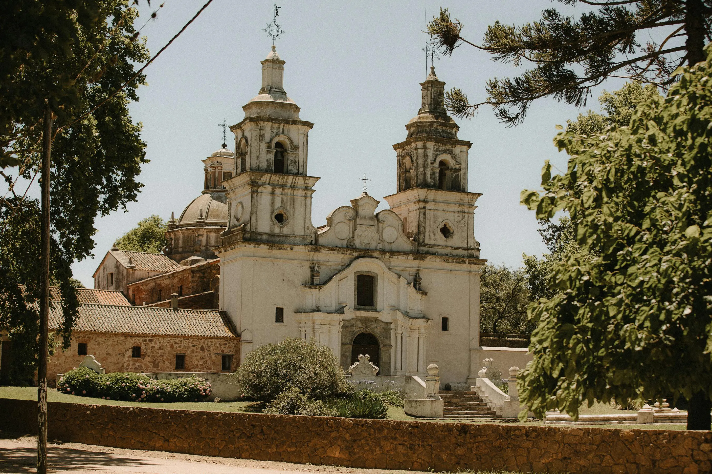 A colonial stone church with a bell tower stands in a wide square in Córdoba, Argentina.