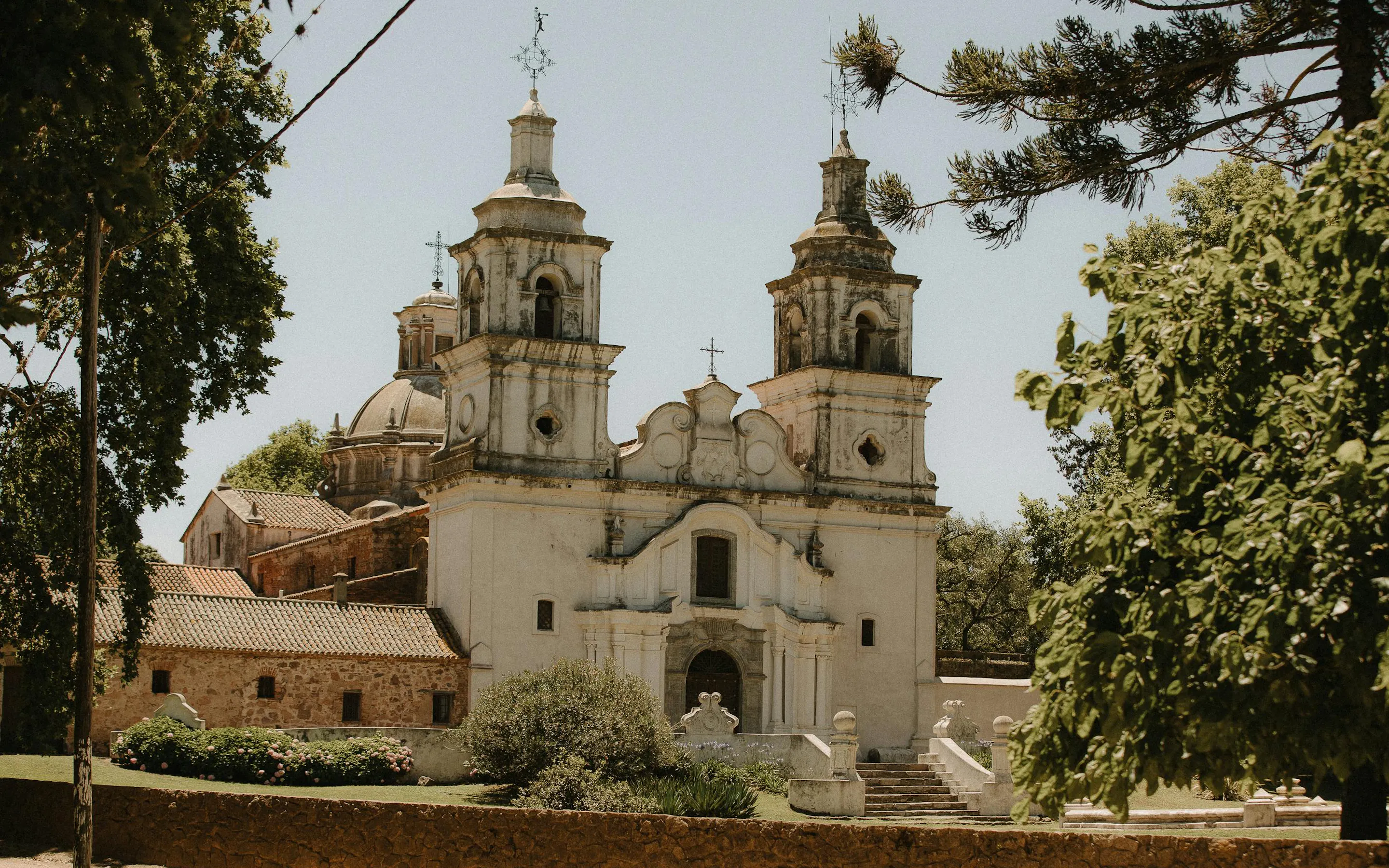 A colonial stone church with a bell tower stands in a wide square in Córdoba, Argentina.