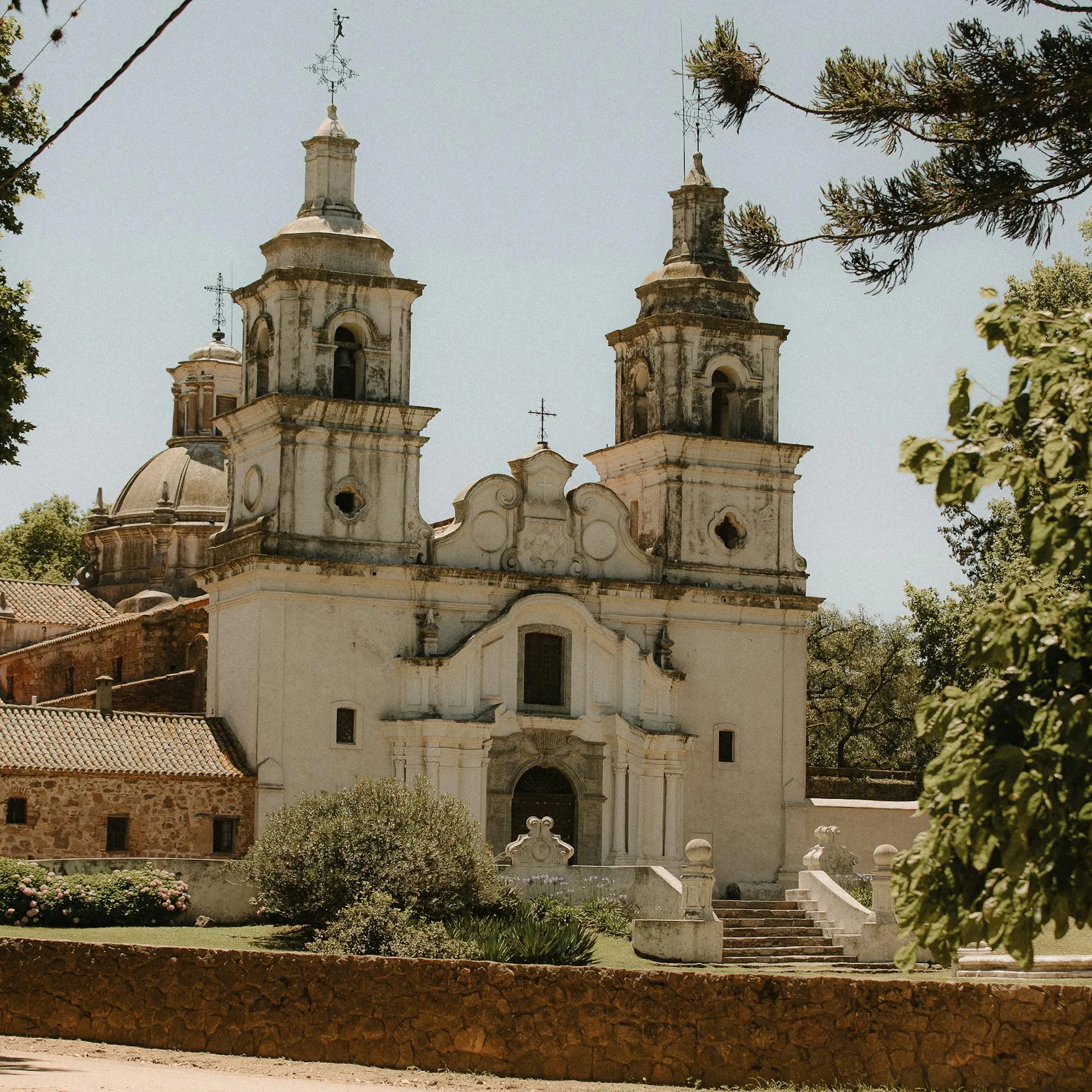 A colonial stone church with a bell tower stands in a wide square in Córdoba, Argentina.