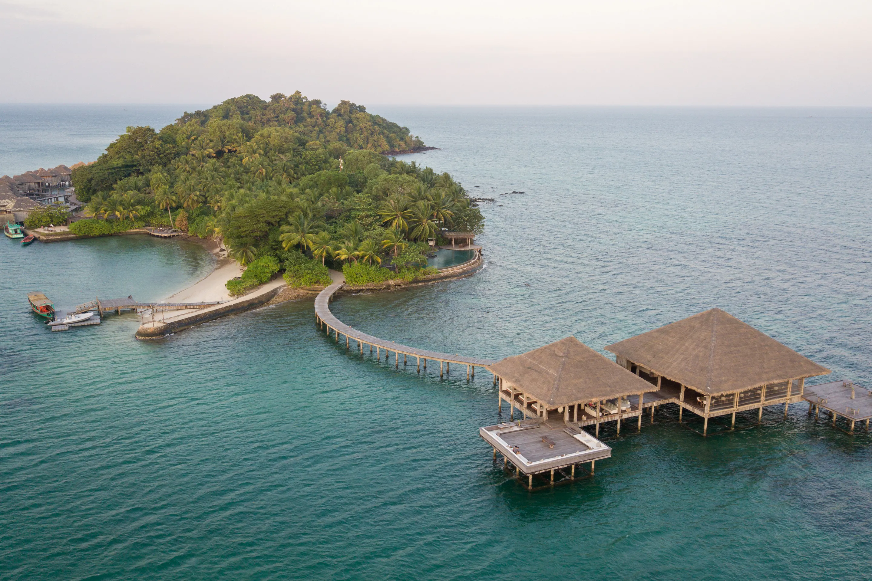 Aerial view of a densely forested island surrounded by vivid turquoise ocean near Koh Rong.