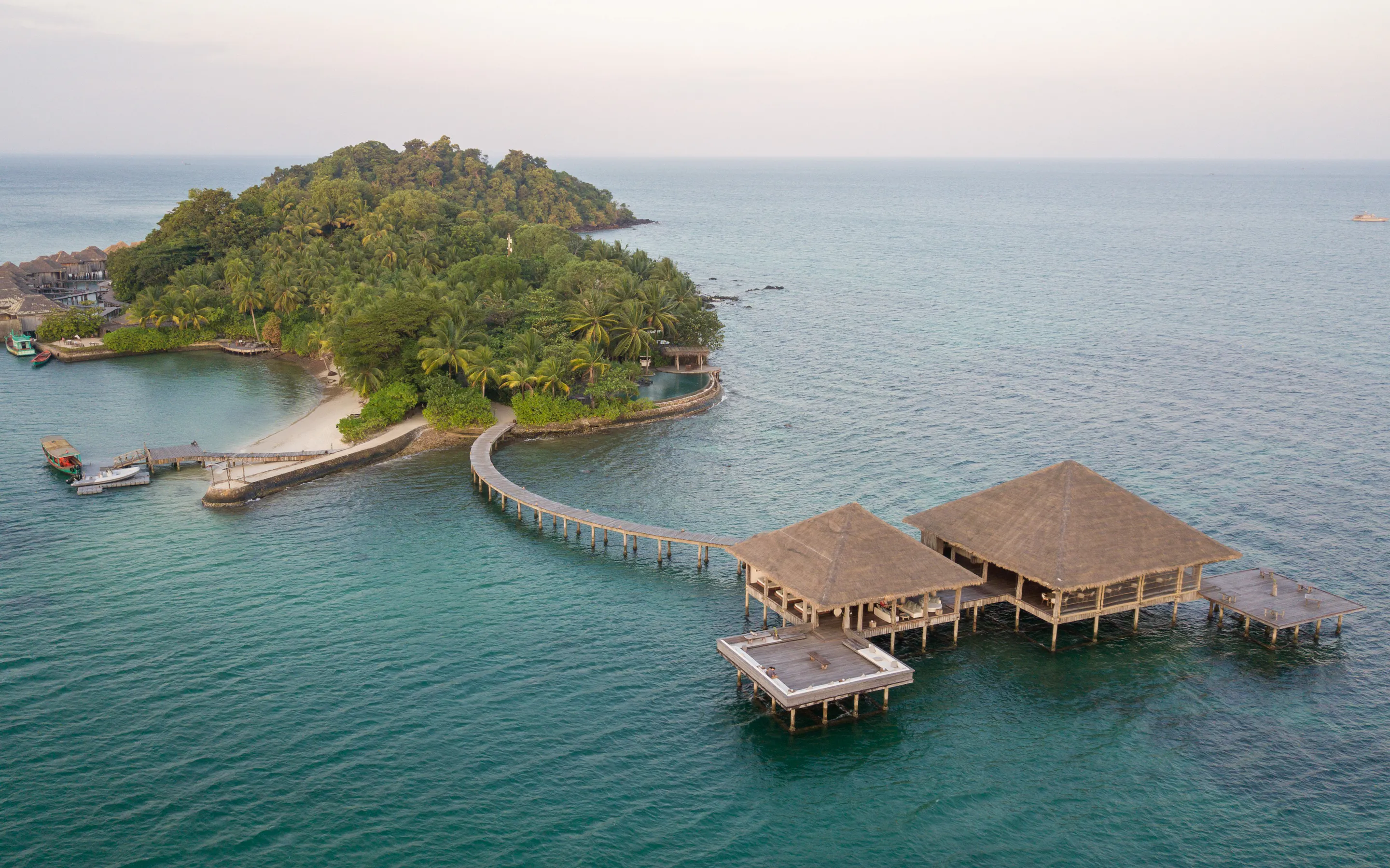 Aerial view of a densely forested island surrounded by vivid turquoise ocean near Koh Rong.