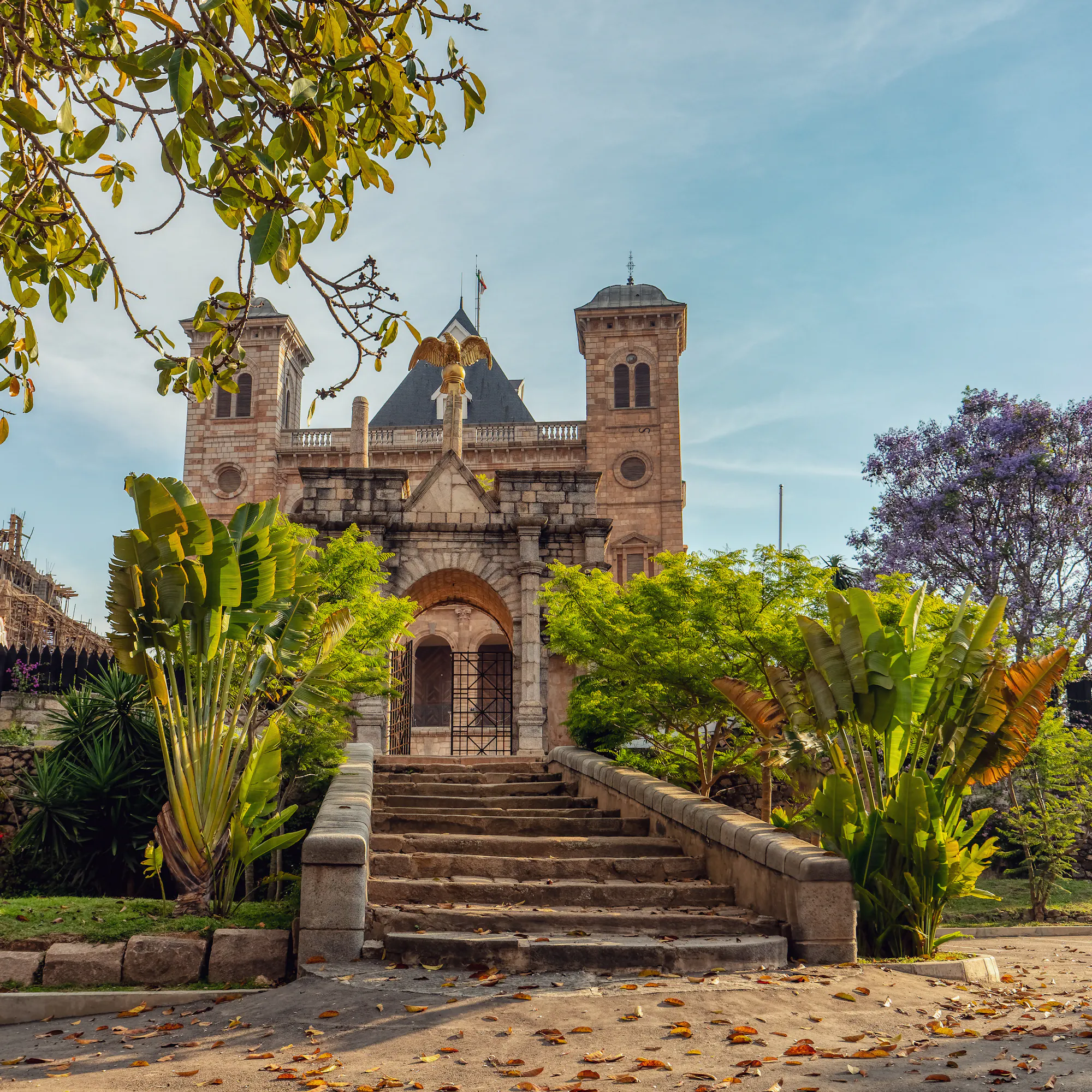 A colonial-era stone church and monument stand amid flower-filled gardens in Antananarivo.