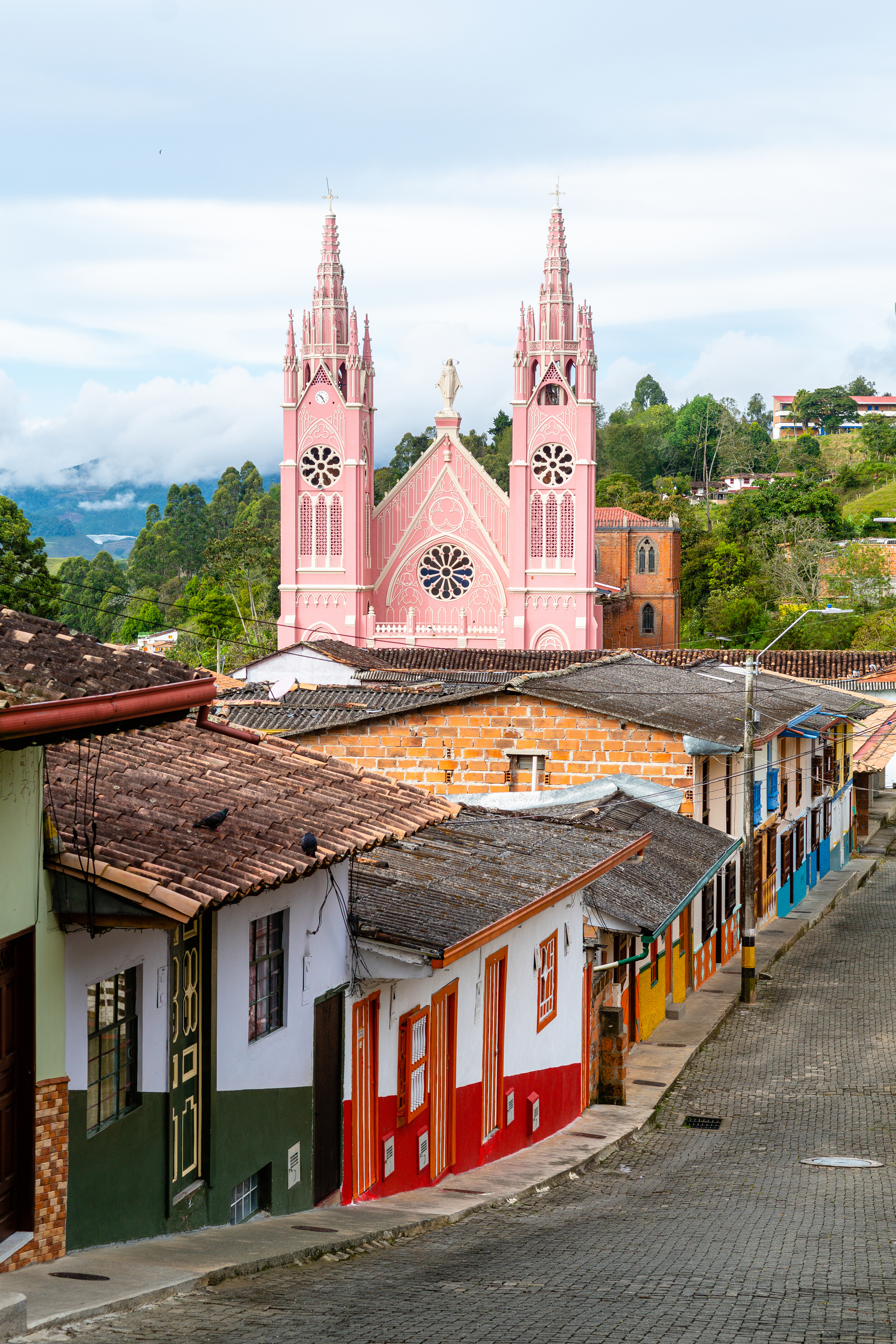 A colorful hilltop colonial town with a pink church and painted facades in Colombia's coffee region.