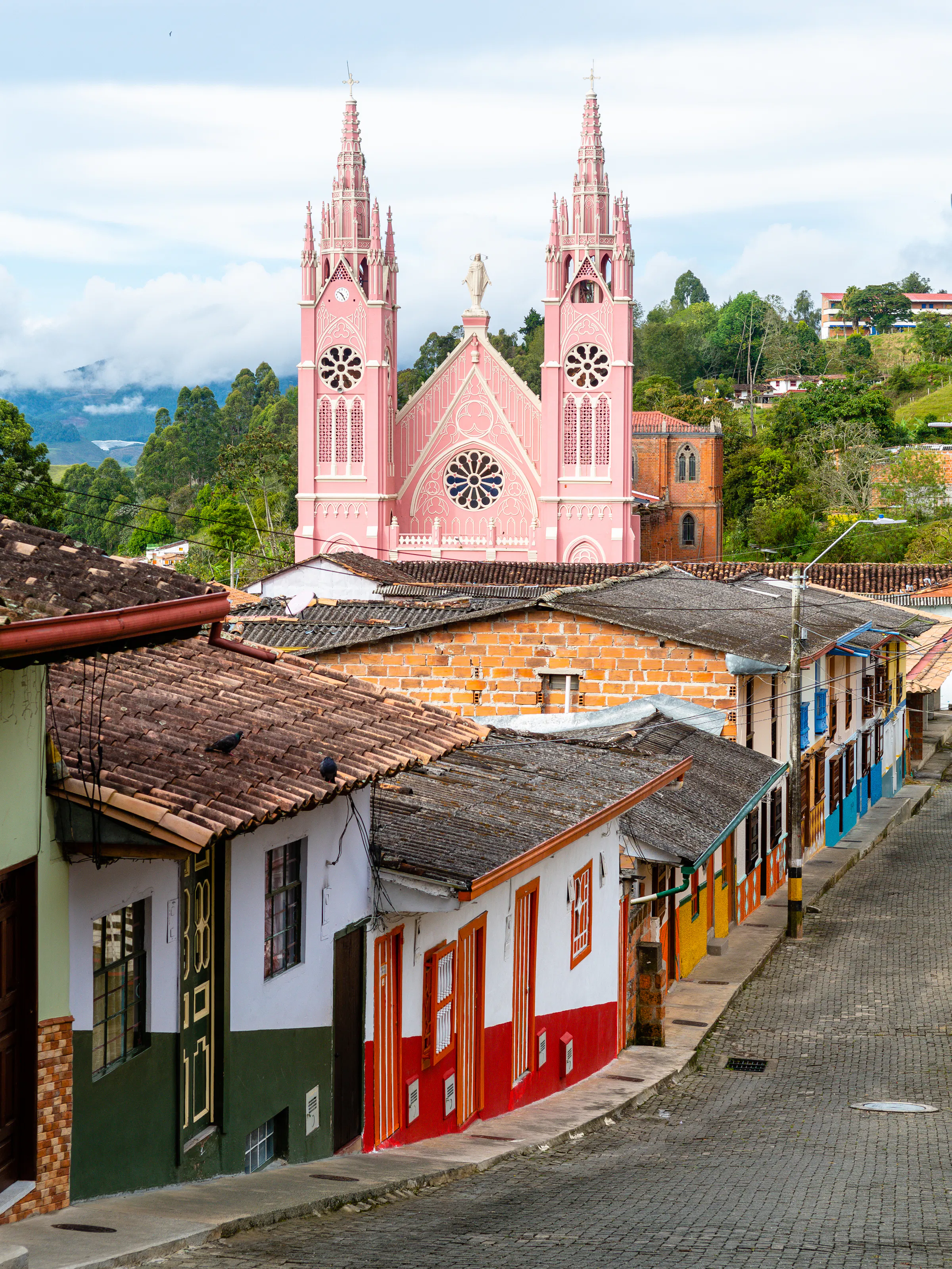 A colorful hilltop colonial town with a pink church and painted facades in Colombia's coffee region.