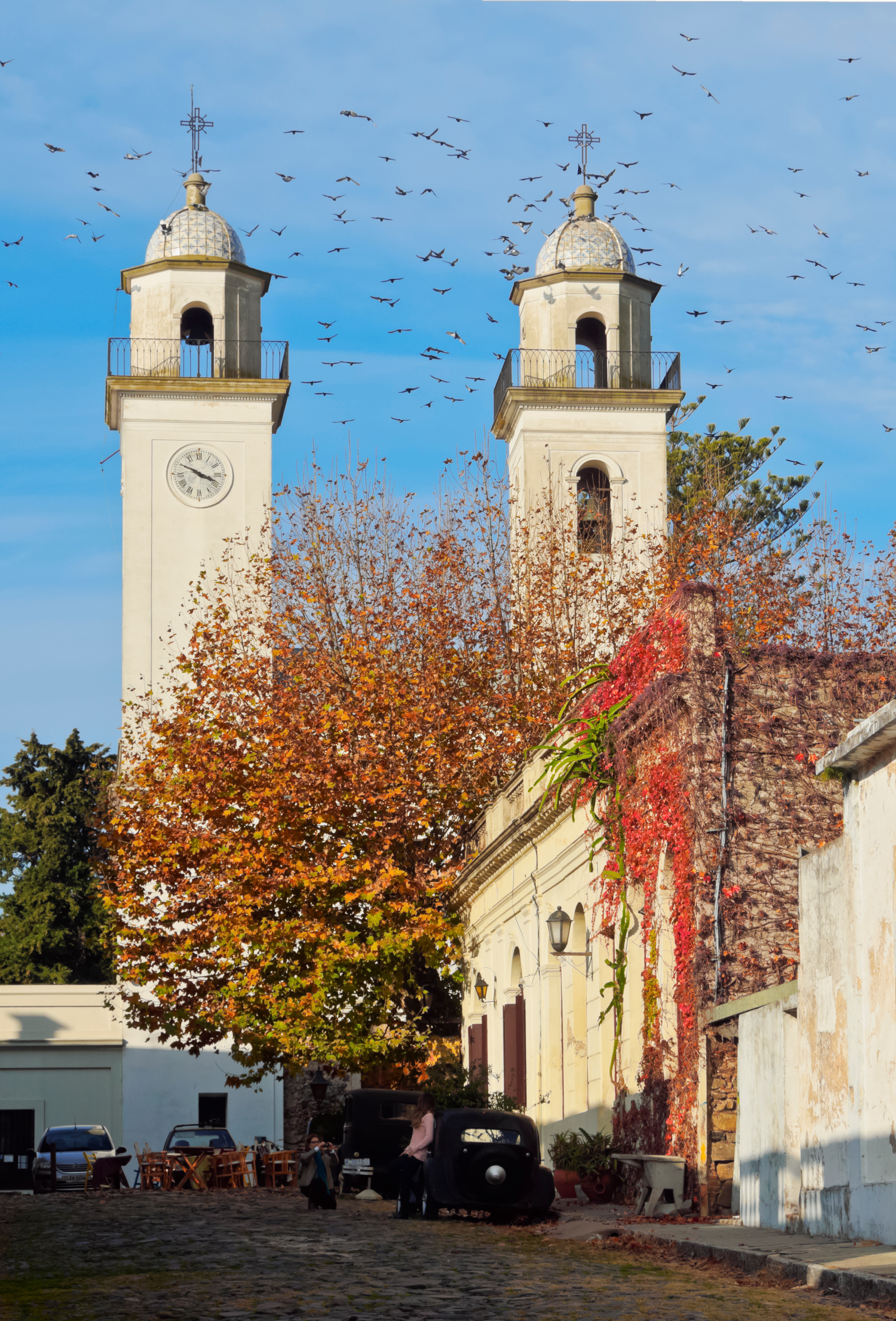 A Baroque church with twin towers and autumn-colored trees on a town plaza in Uruguay.