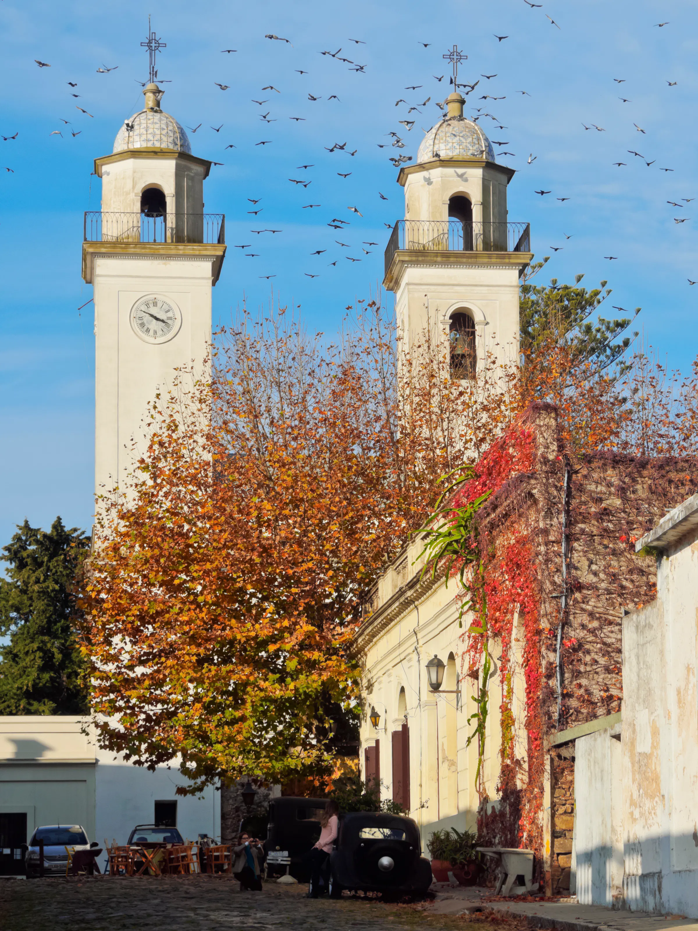 A Baroque church with twin towers and autumn-colored trees on a town plaza in Uruguay.