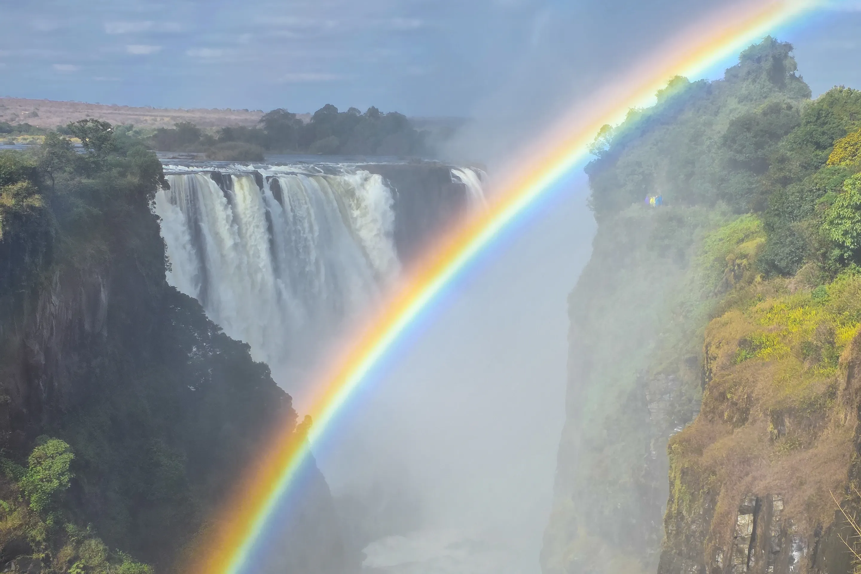 Victoria Falls thunders into a deep gorge beneath a vivid rainbow arching through the mist.