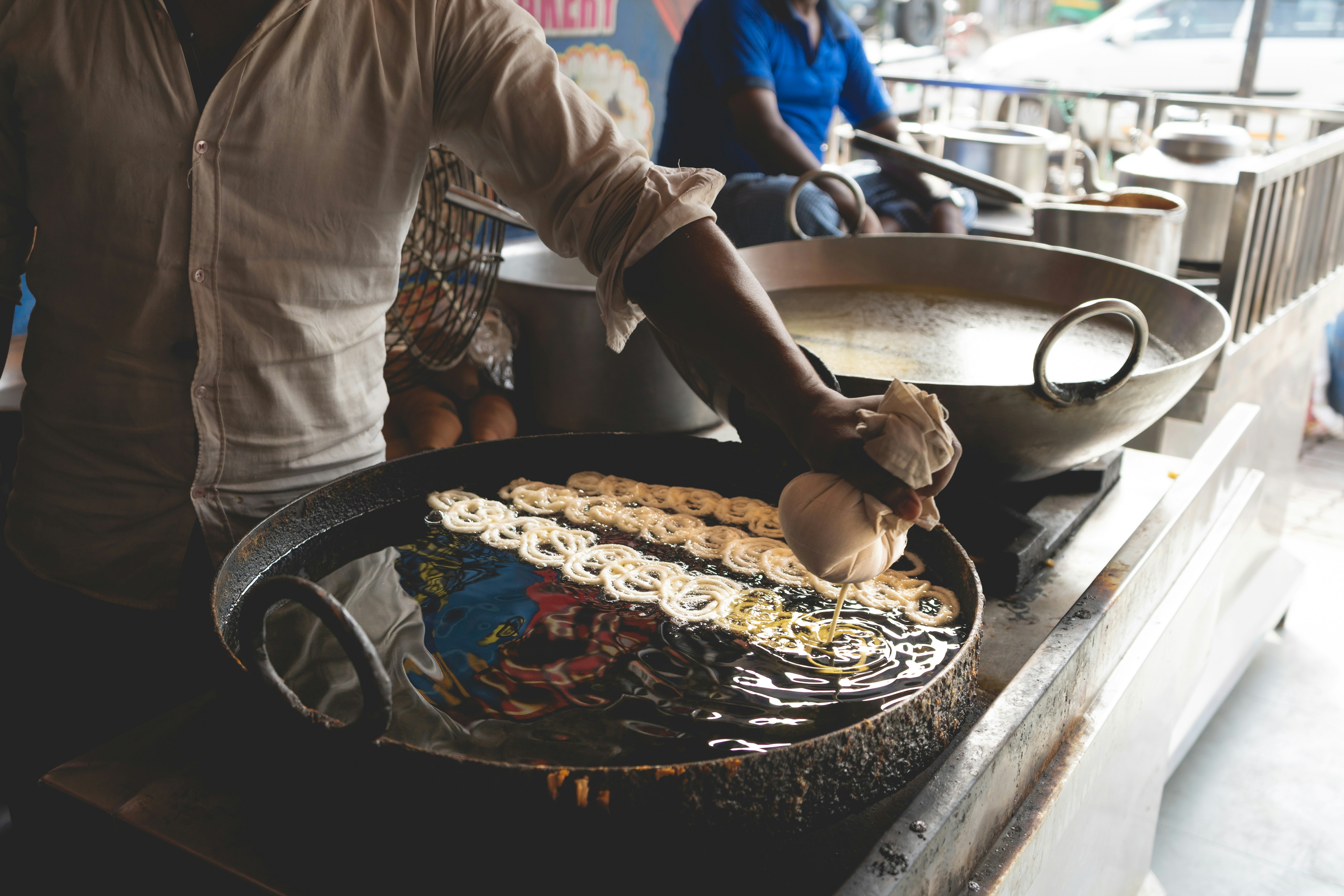 Street vendor frying jalebi in hot oil at a market in Congo