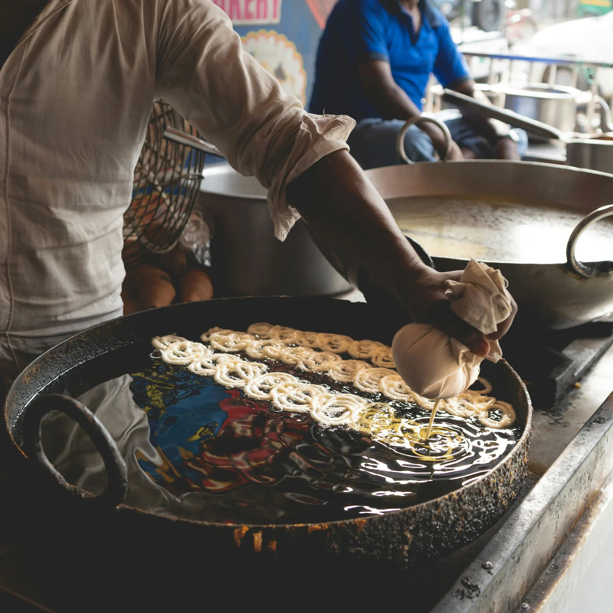 Street vendor frying jalebi in hot oil at a market in Congo