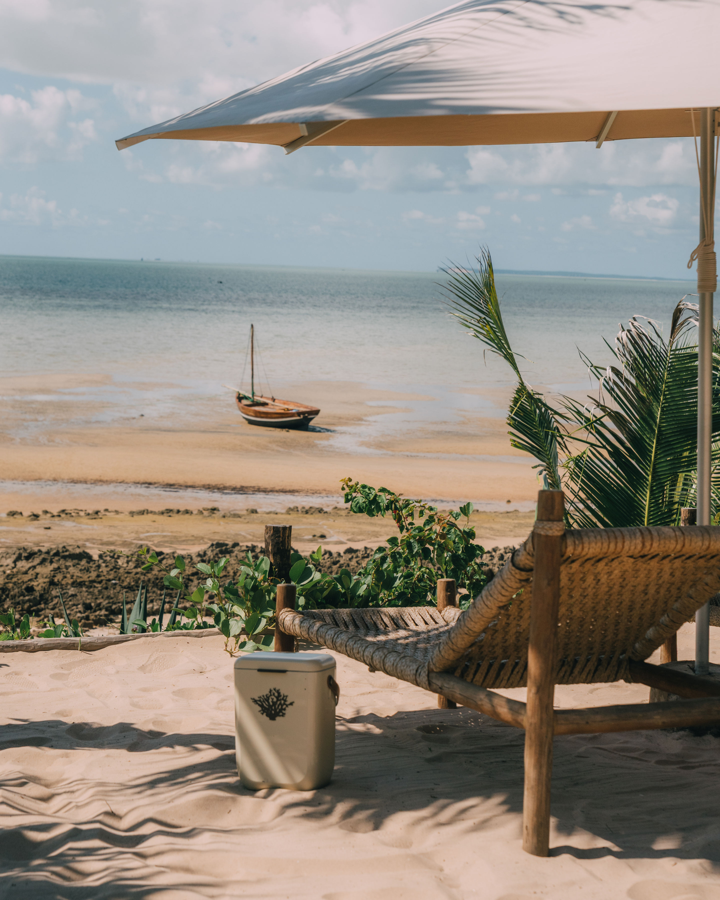 Rattan beach lounger with dhow sailboat on Mozambique shore