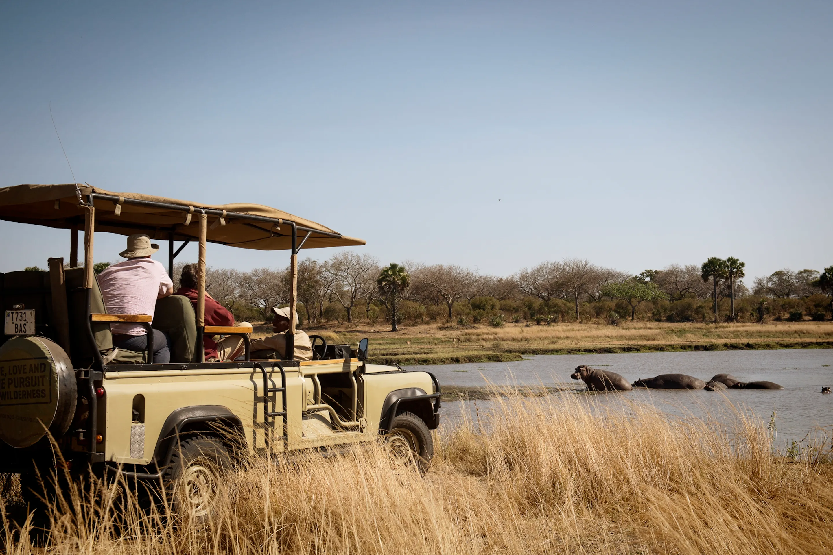Safari vehicle watching a pod of hippos at a waterhole in Katavi National Park, Tanzania