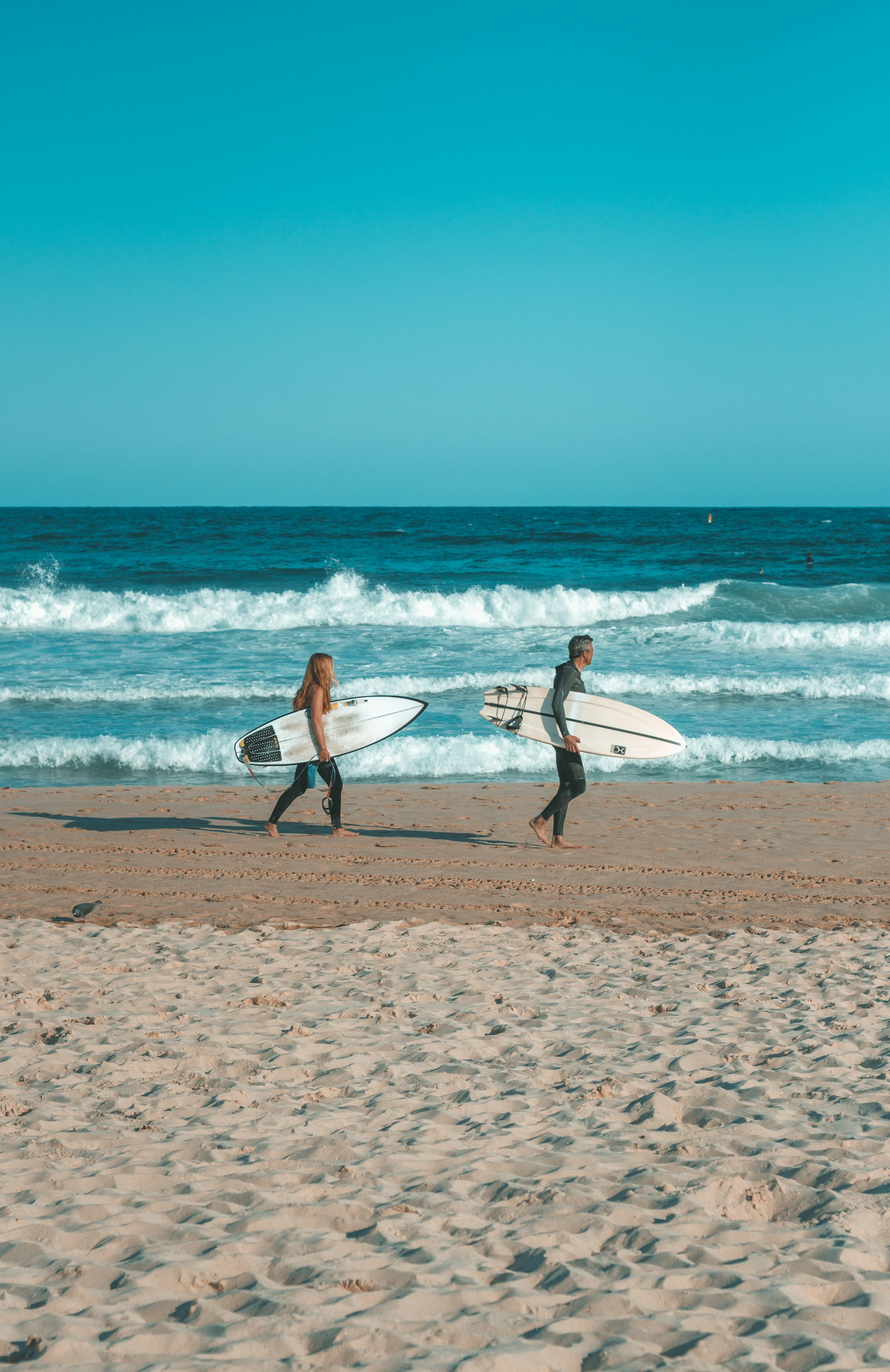 Two surfers carrying boards on Bondi Beach, Sydney Australia