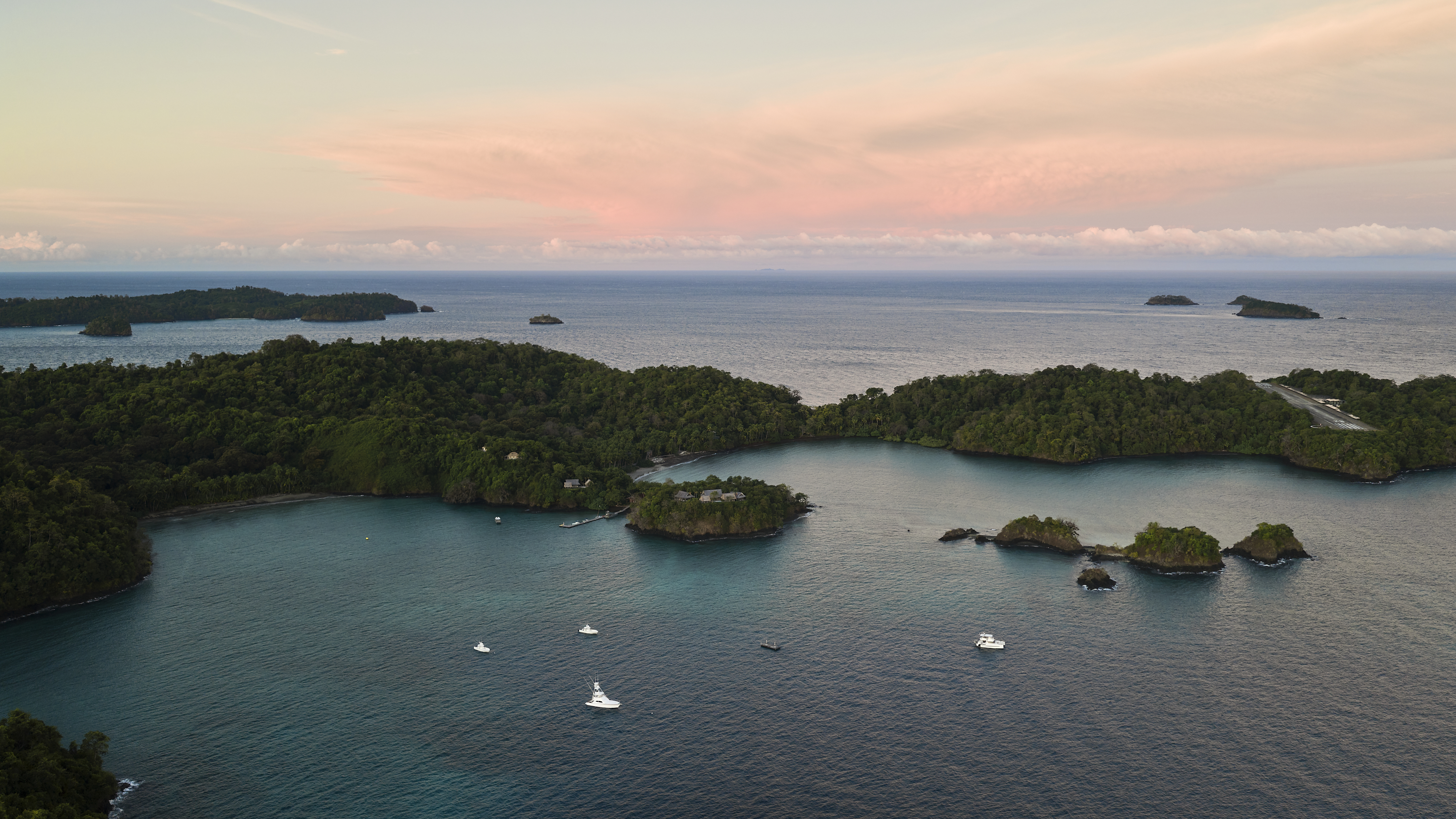 Aerial view of boats anchored among forested islands at sunset near Paridas Island, Panama