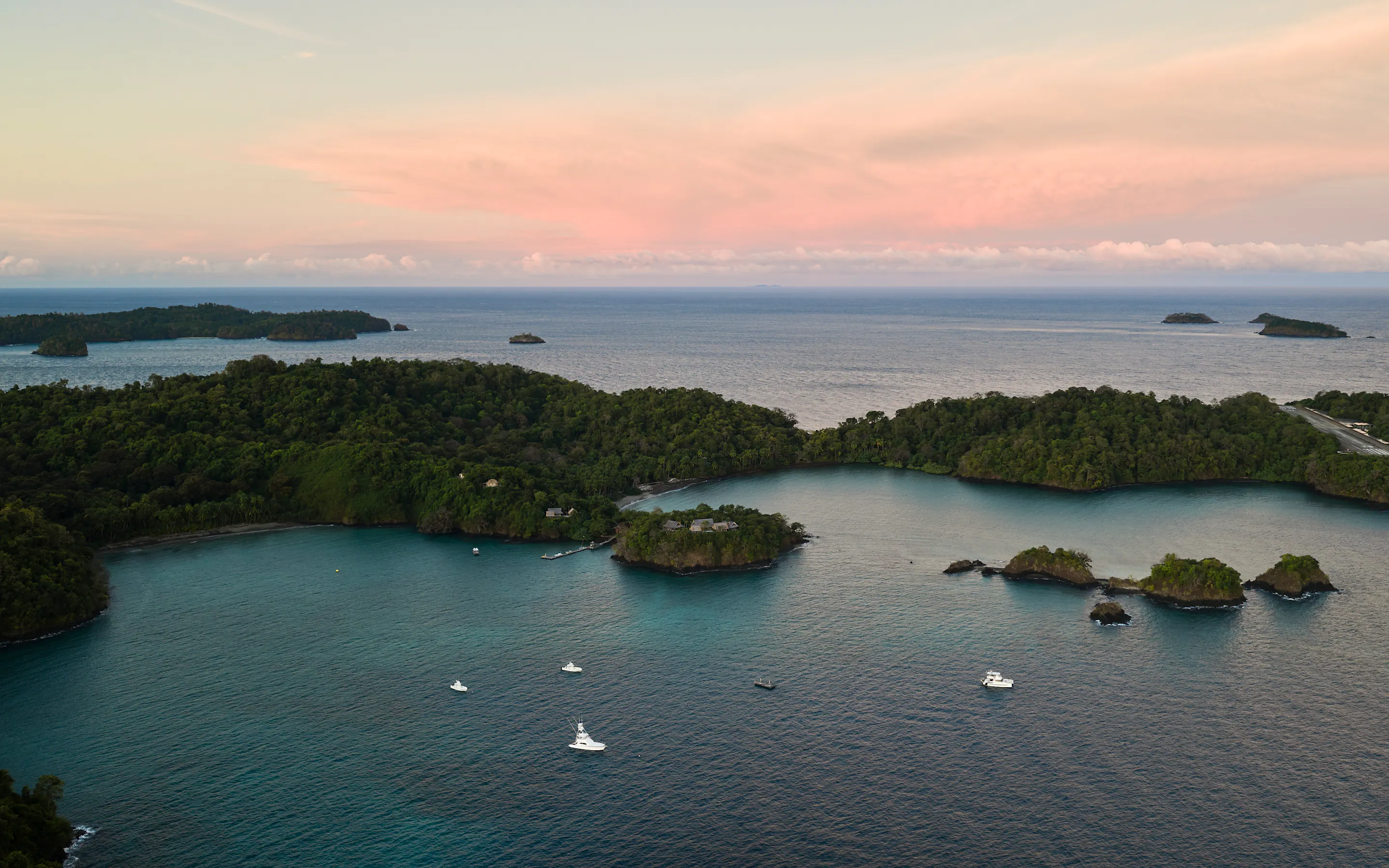 Aerial view of boats anchored among forested islands at sunset near Paridas Island, Panama