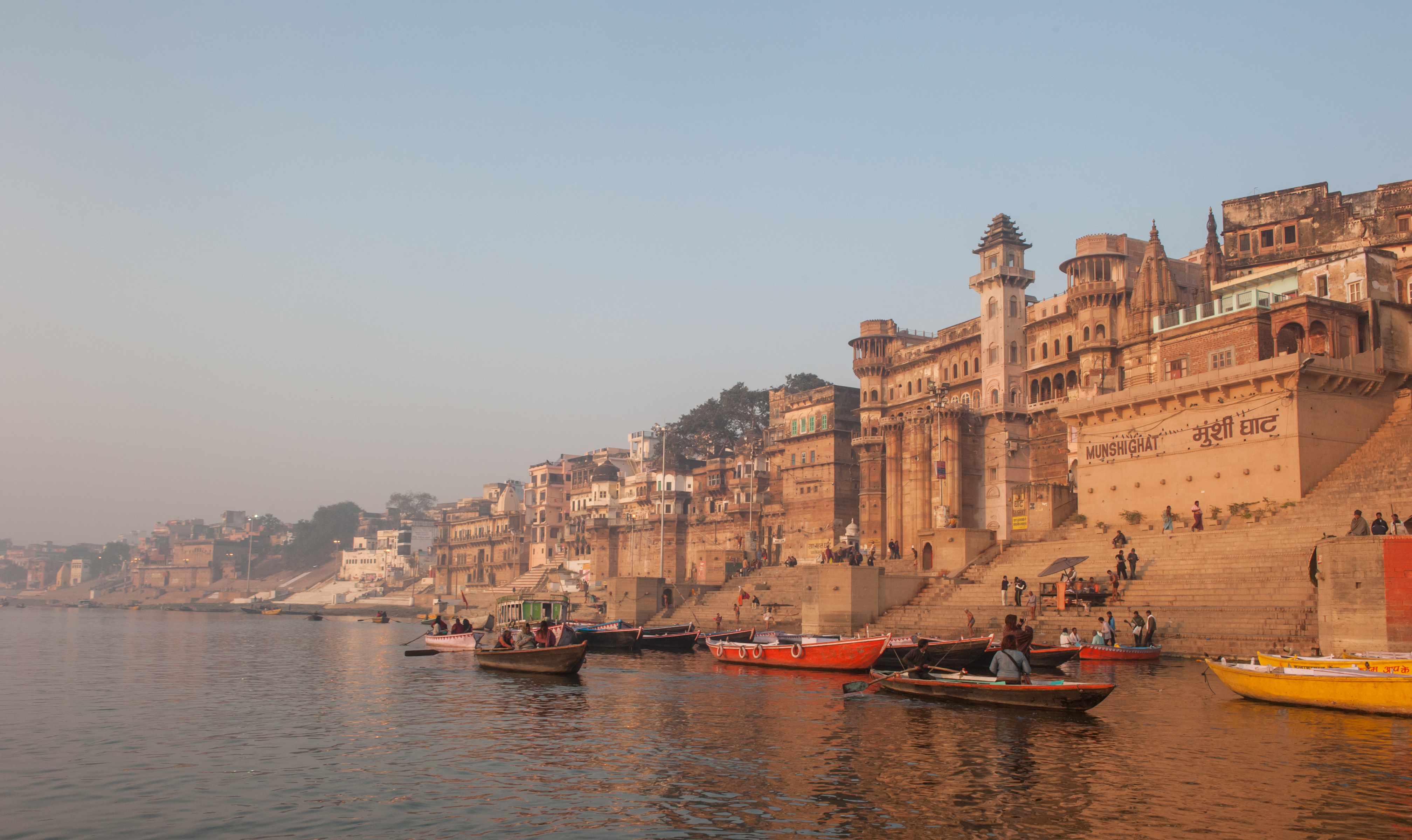 Munshi Ghat riverfront palace and boats on the Ganges River in Varanasi, India at sunrise