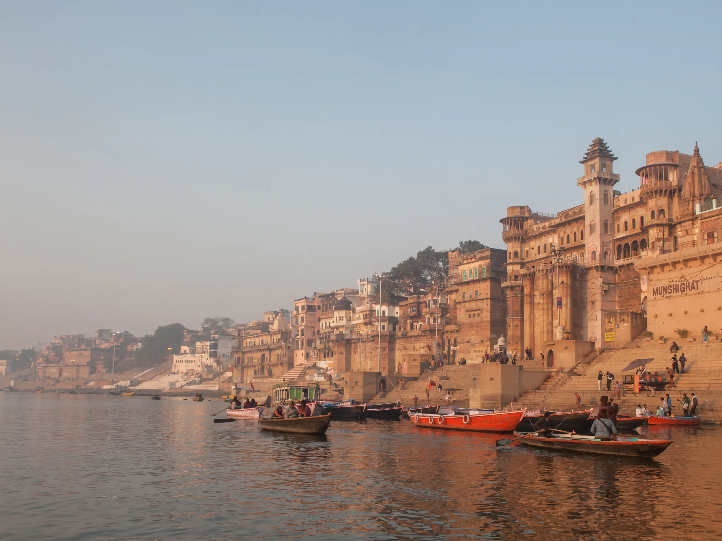 Munshi Ghat riverfront palace and boats on the Ganges River in Varanasi, India at sunrise