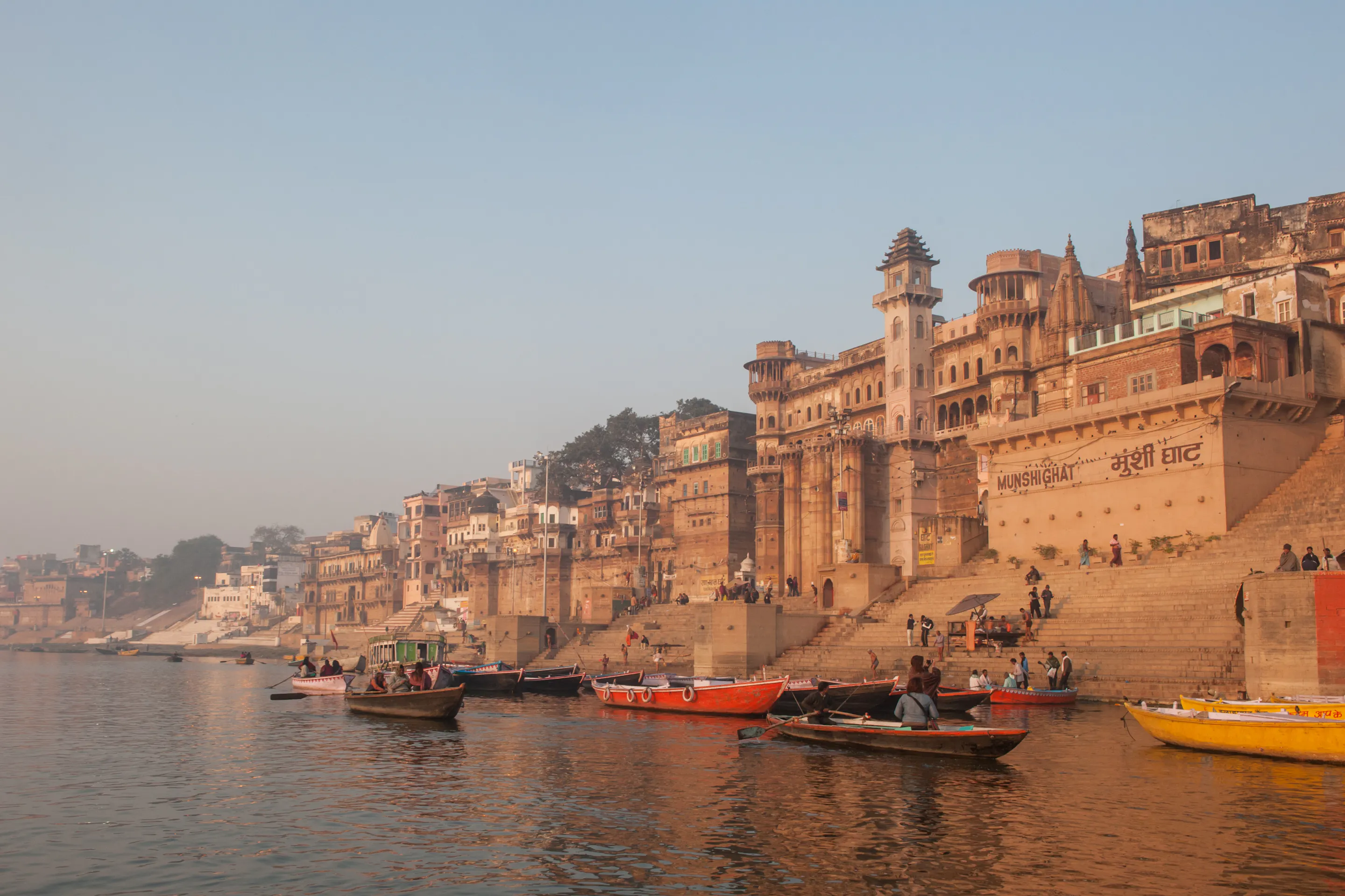 Munshi Ghat riverfront palace and boats on the Ganges River in Varanasi, India at sunrise