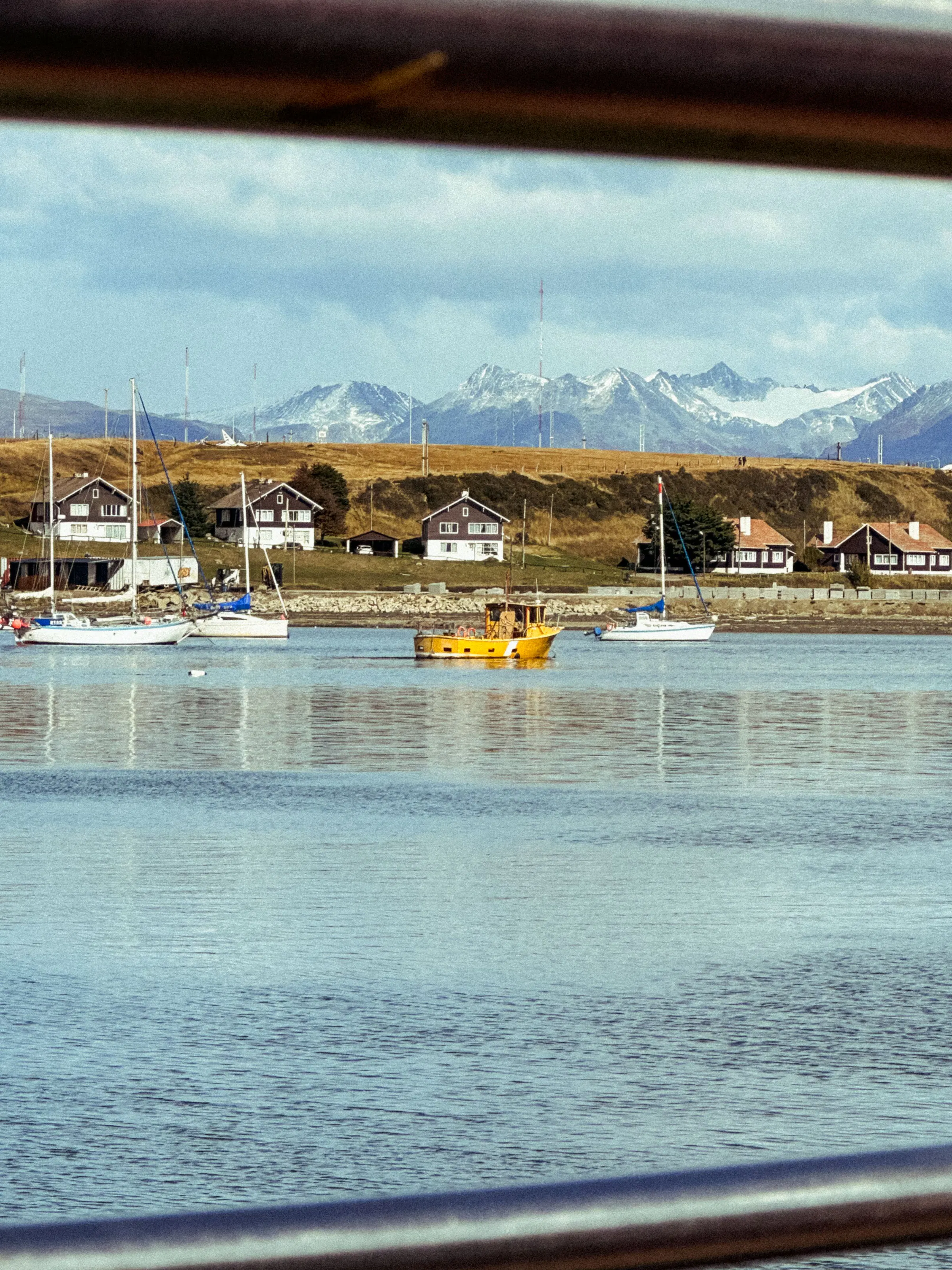 Yellow boat in Ushuaia harbor with snow-capped Andes beyond