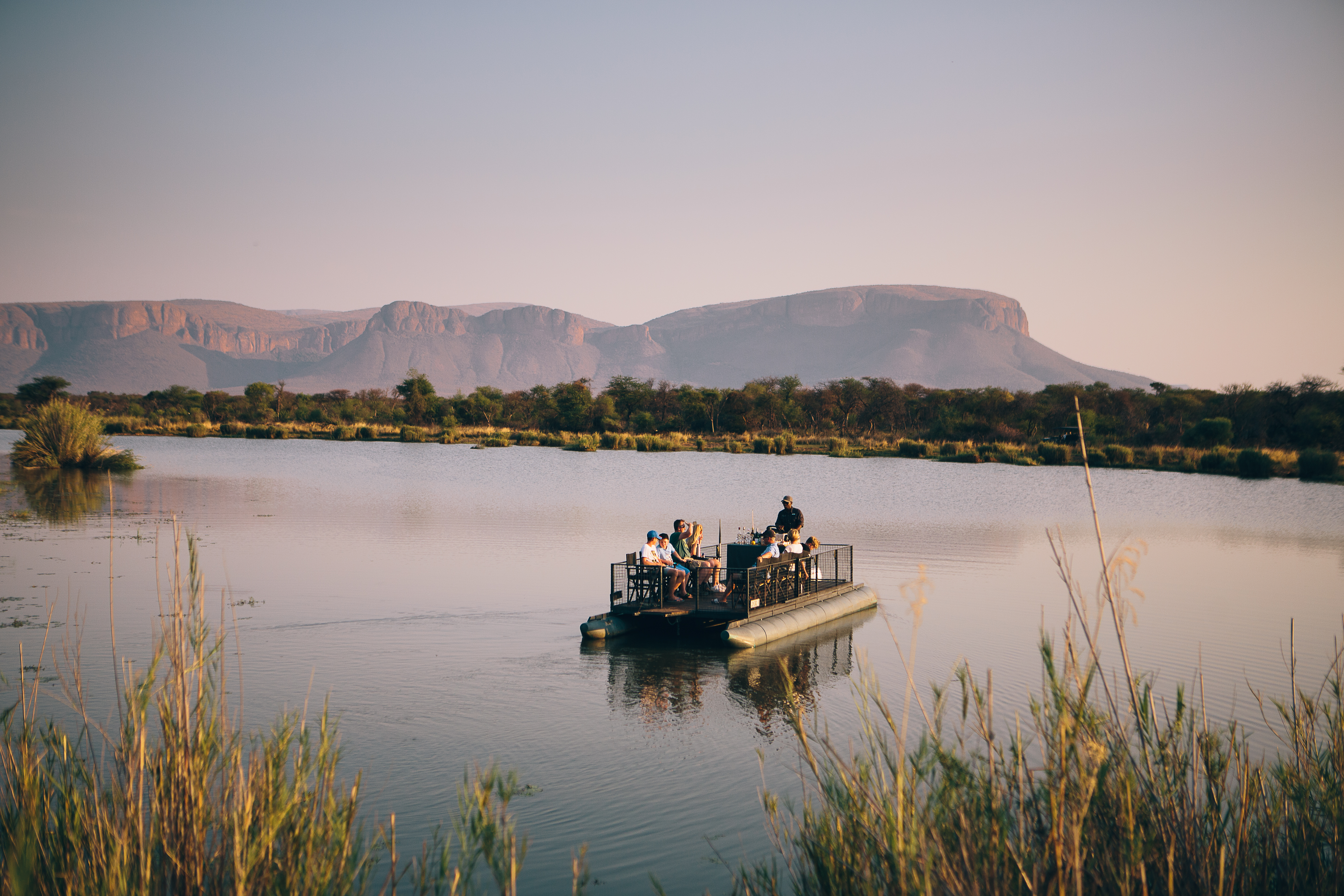 Guests on a sunset boat safari at Marataba with Waterberg mountains in the background, South Africa