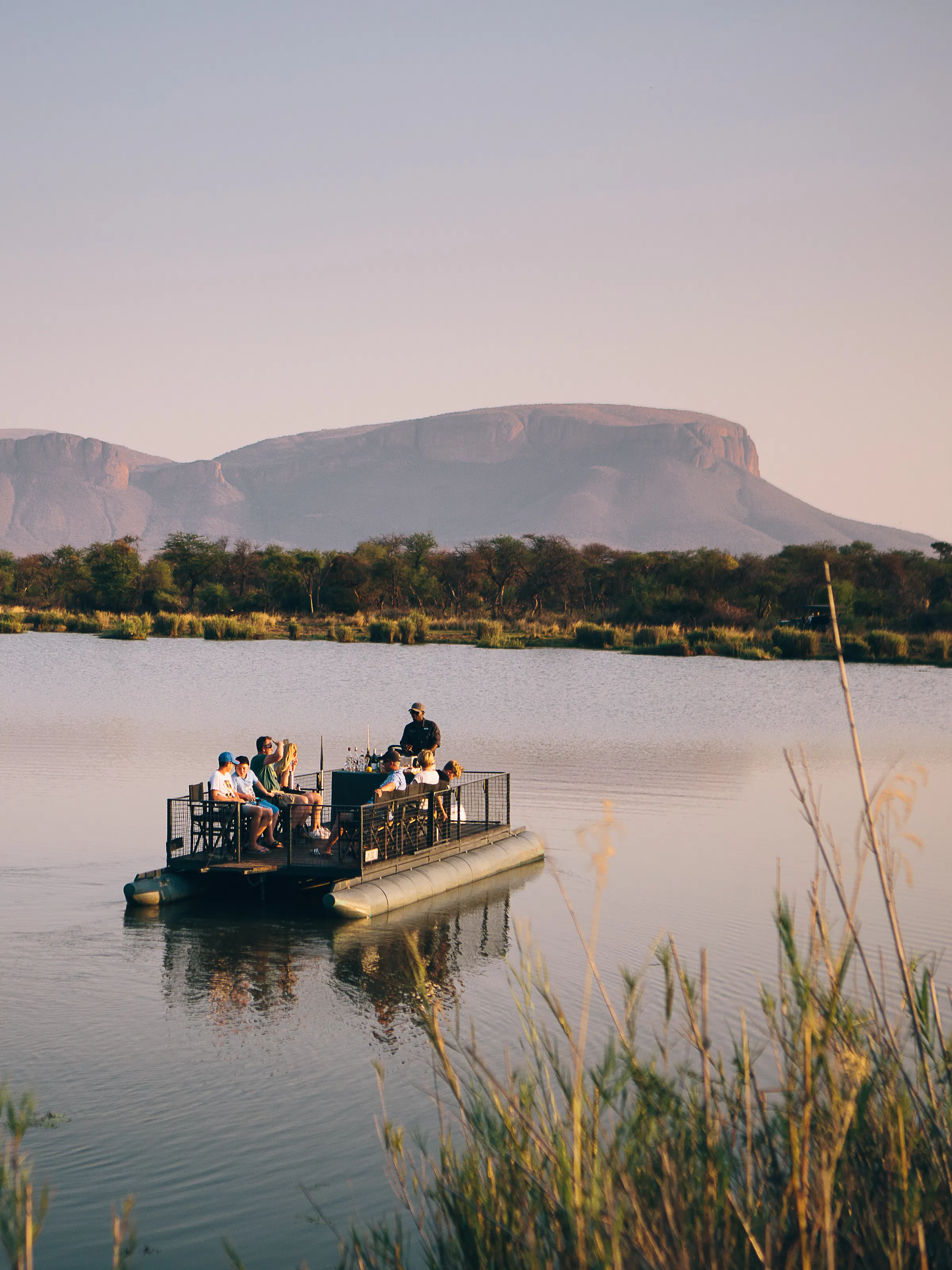 Guests on a sunset boat safari at Marataba with Waterberg mountains in the background, South Africa