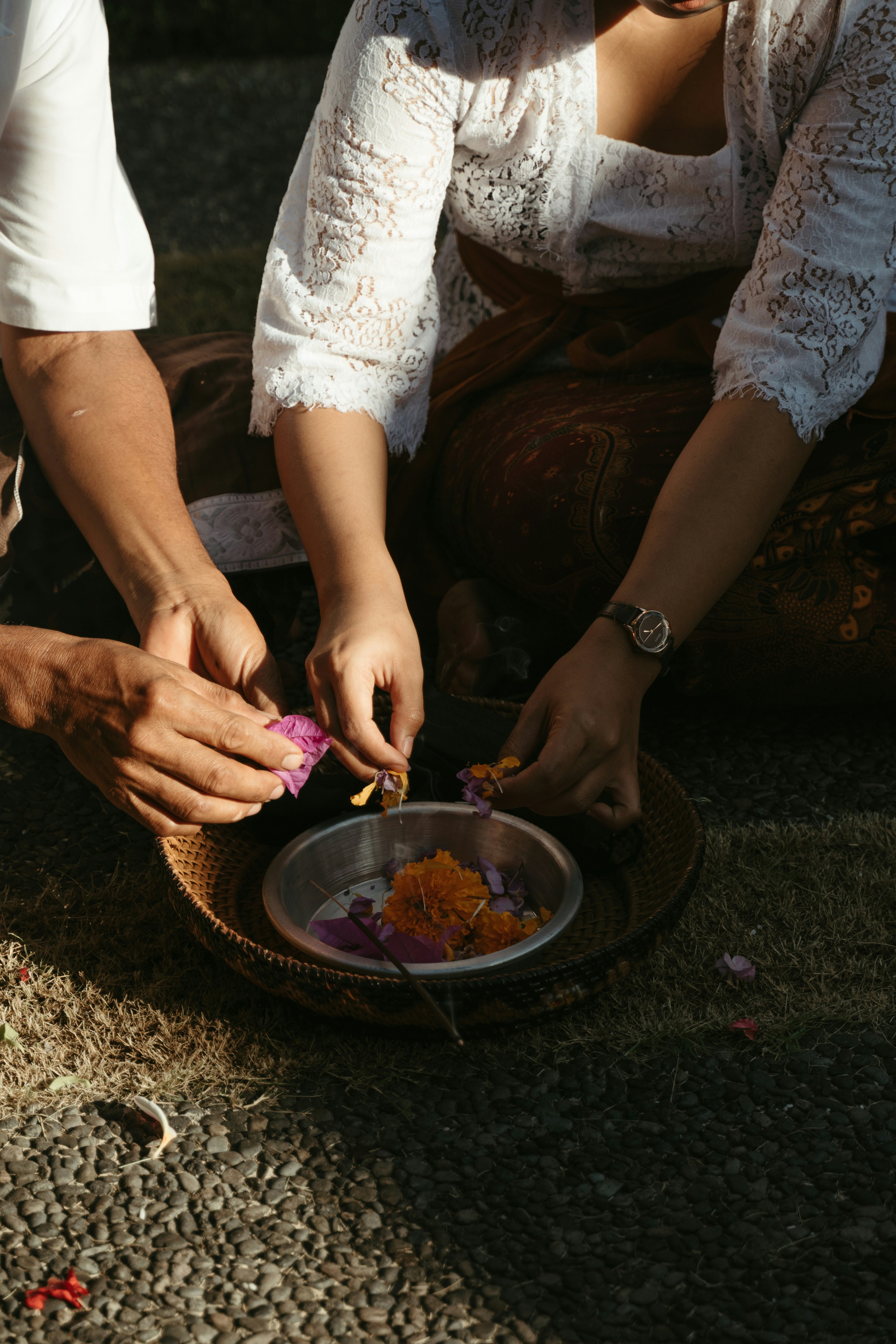 Woman in white shirt arranges an offering during a Galungan ceremony