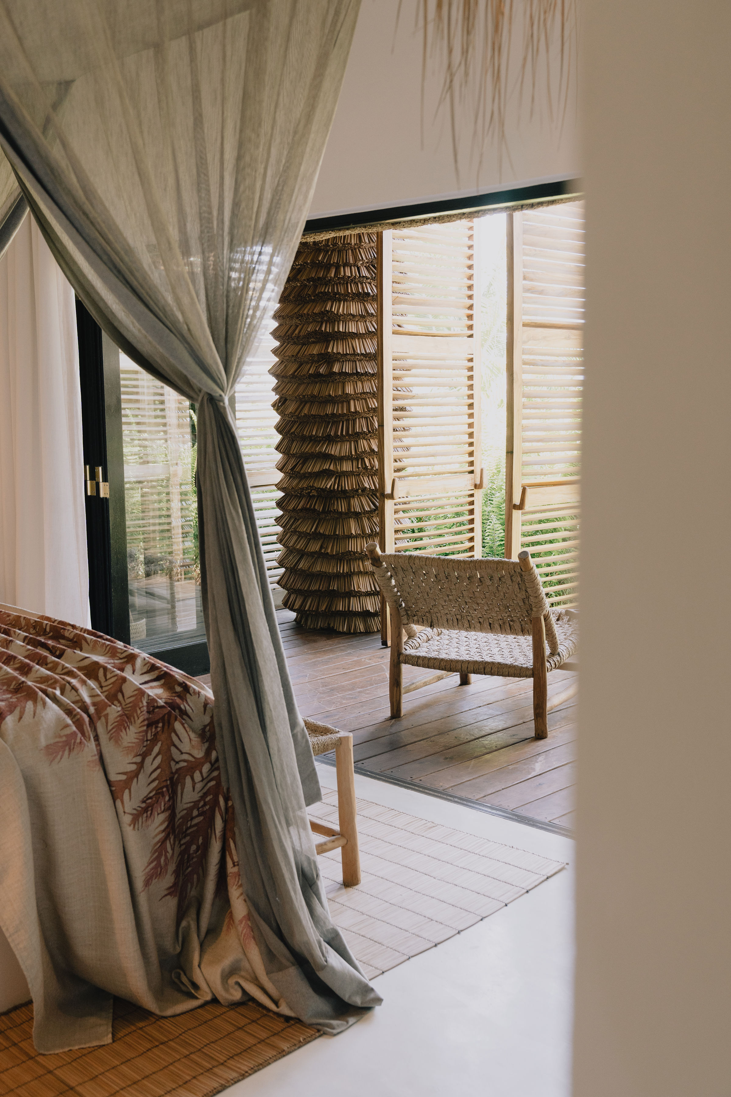 Canopied beach villa bedroom with woven chair thatched Mozambique lodge