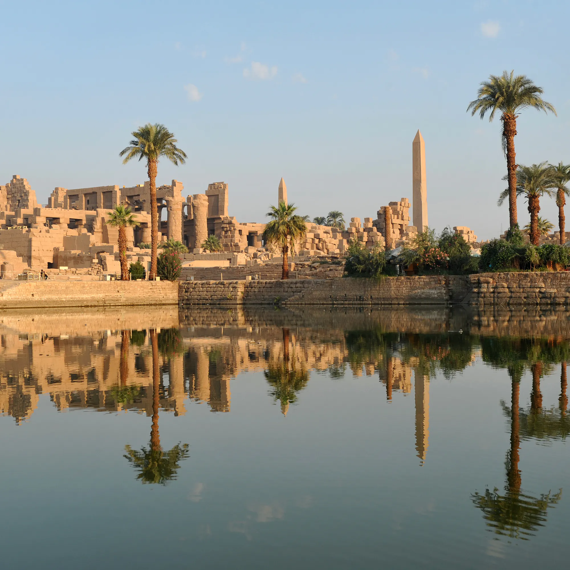 Karnak Temple obelisk and palms reflected in river, Egypt