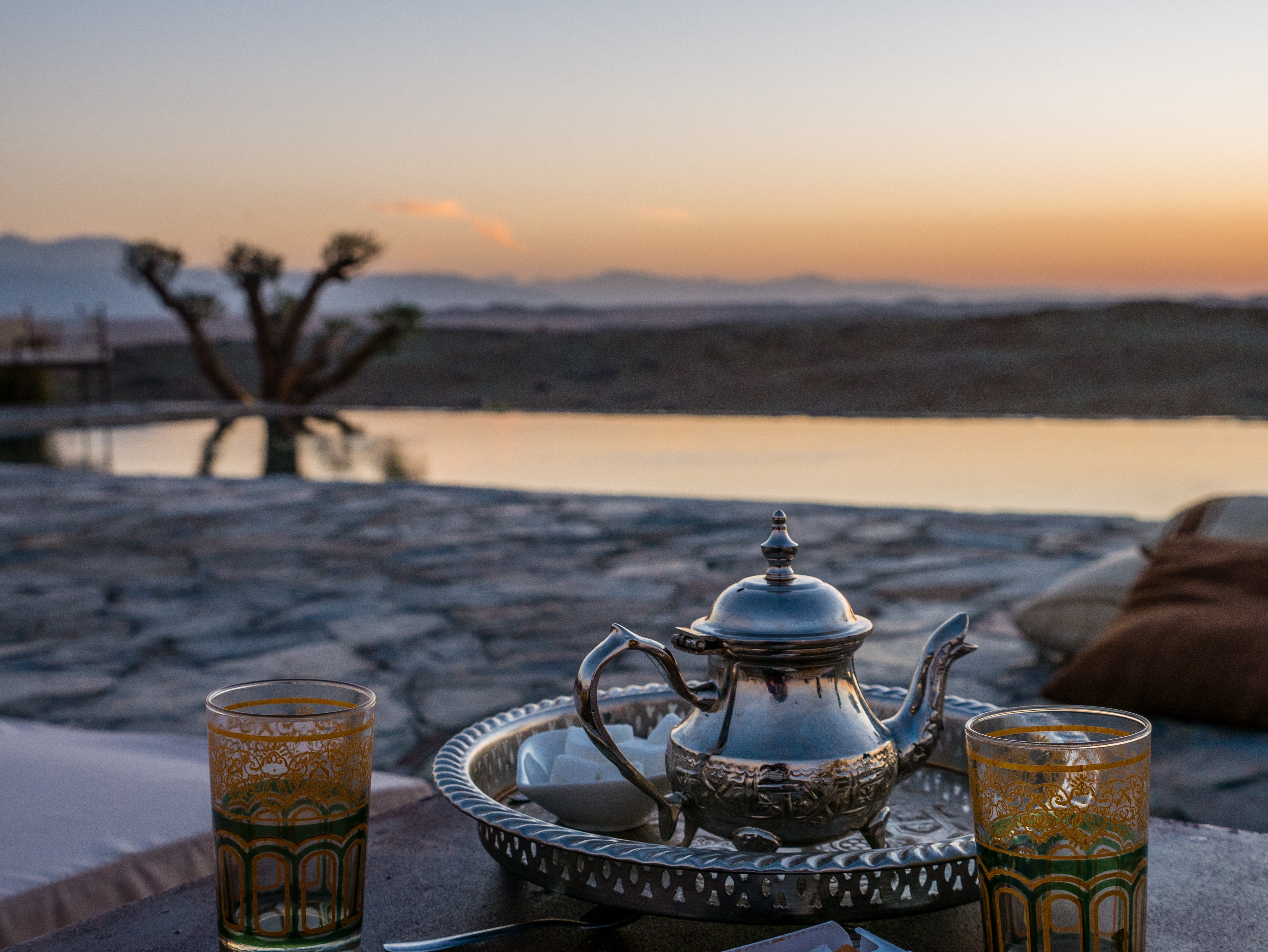 Moroccan silver tea set beside an infinity pool in the Agafay Desert, Morocco