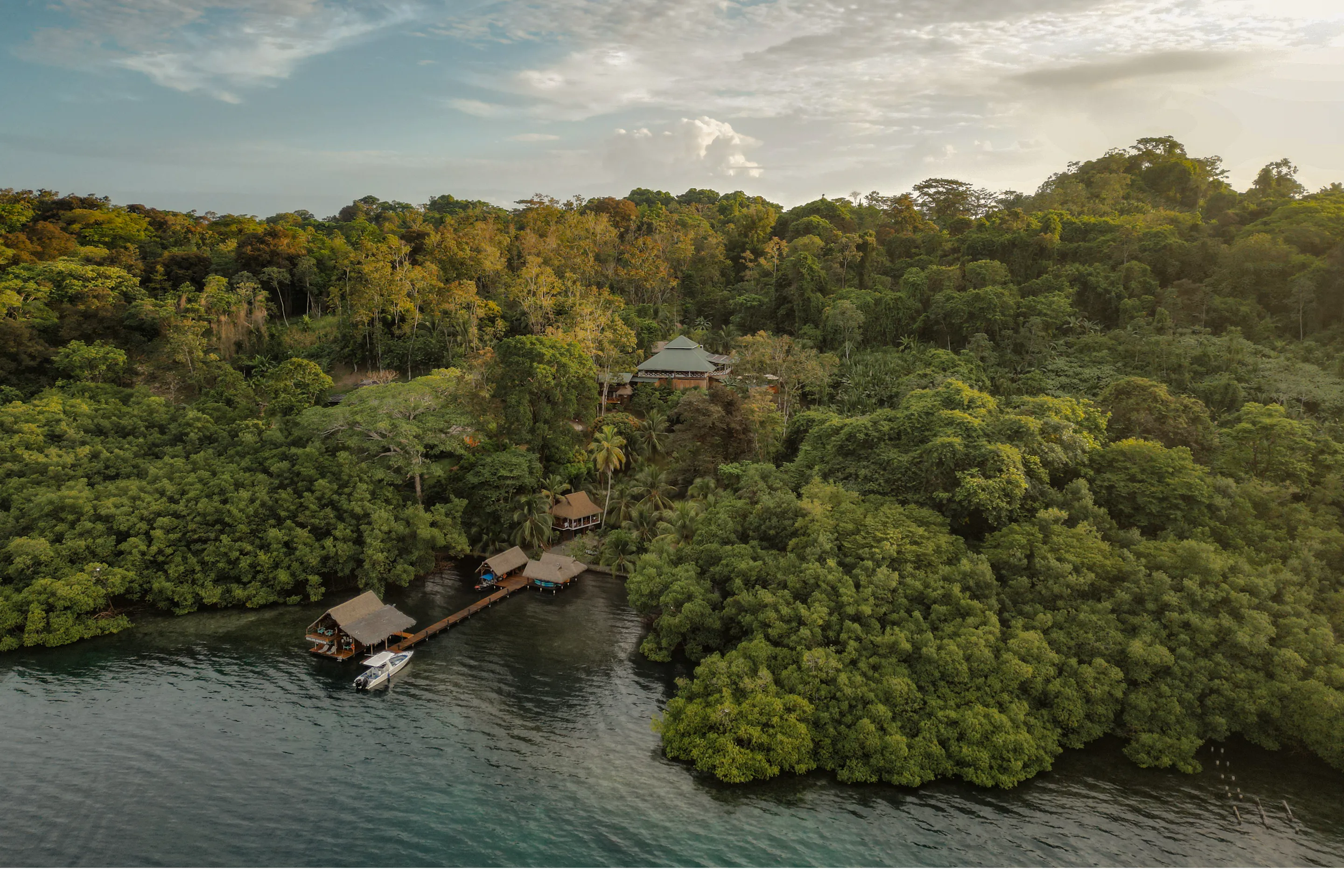 Aerial view of an overwater lodge and dock nestled in the rainforest of Bocas del Toro, Panama
