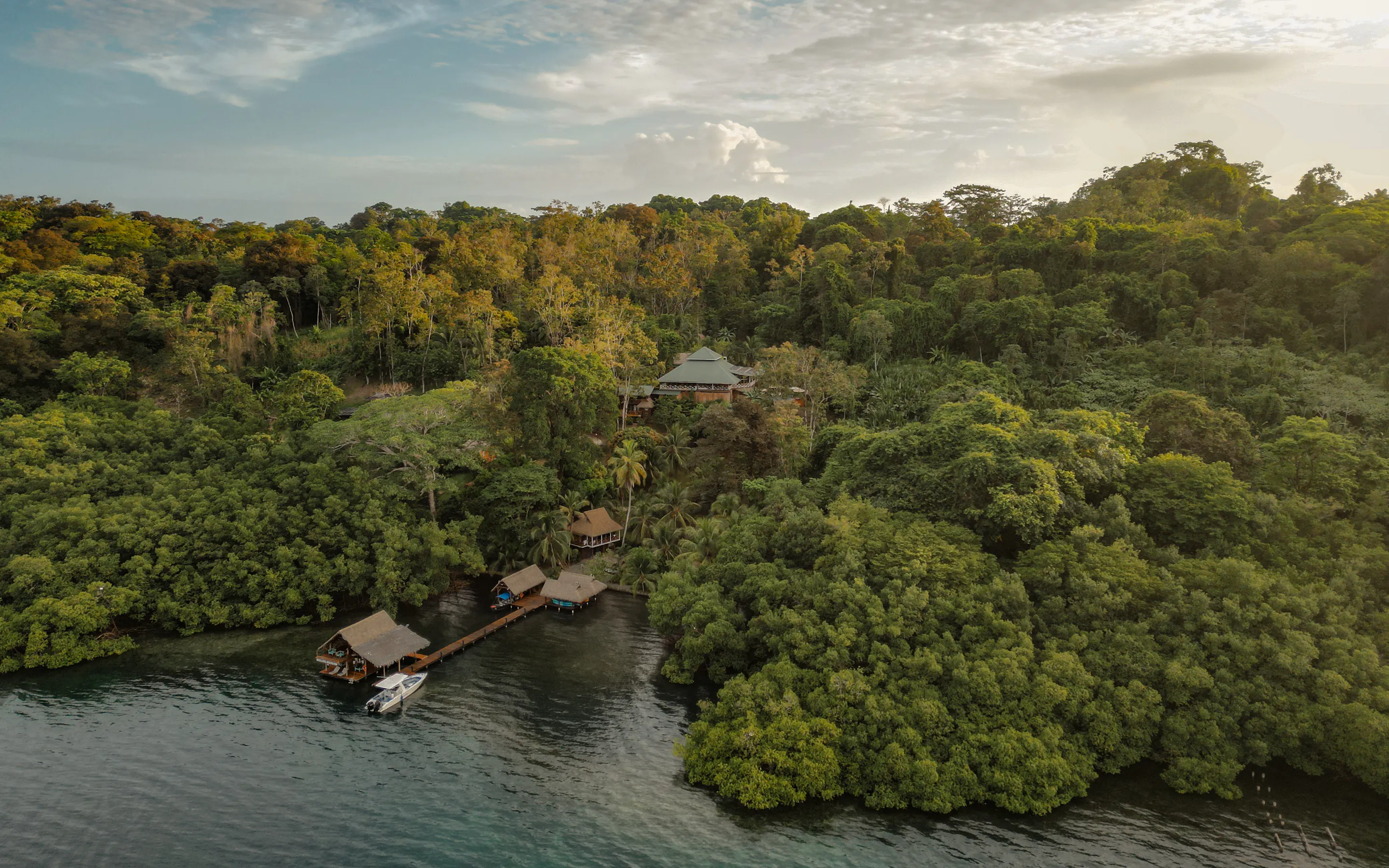 Aerial view of an overwater lodge and dock nestled in the rainforest of Bocas del Toro, Panama