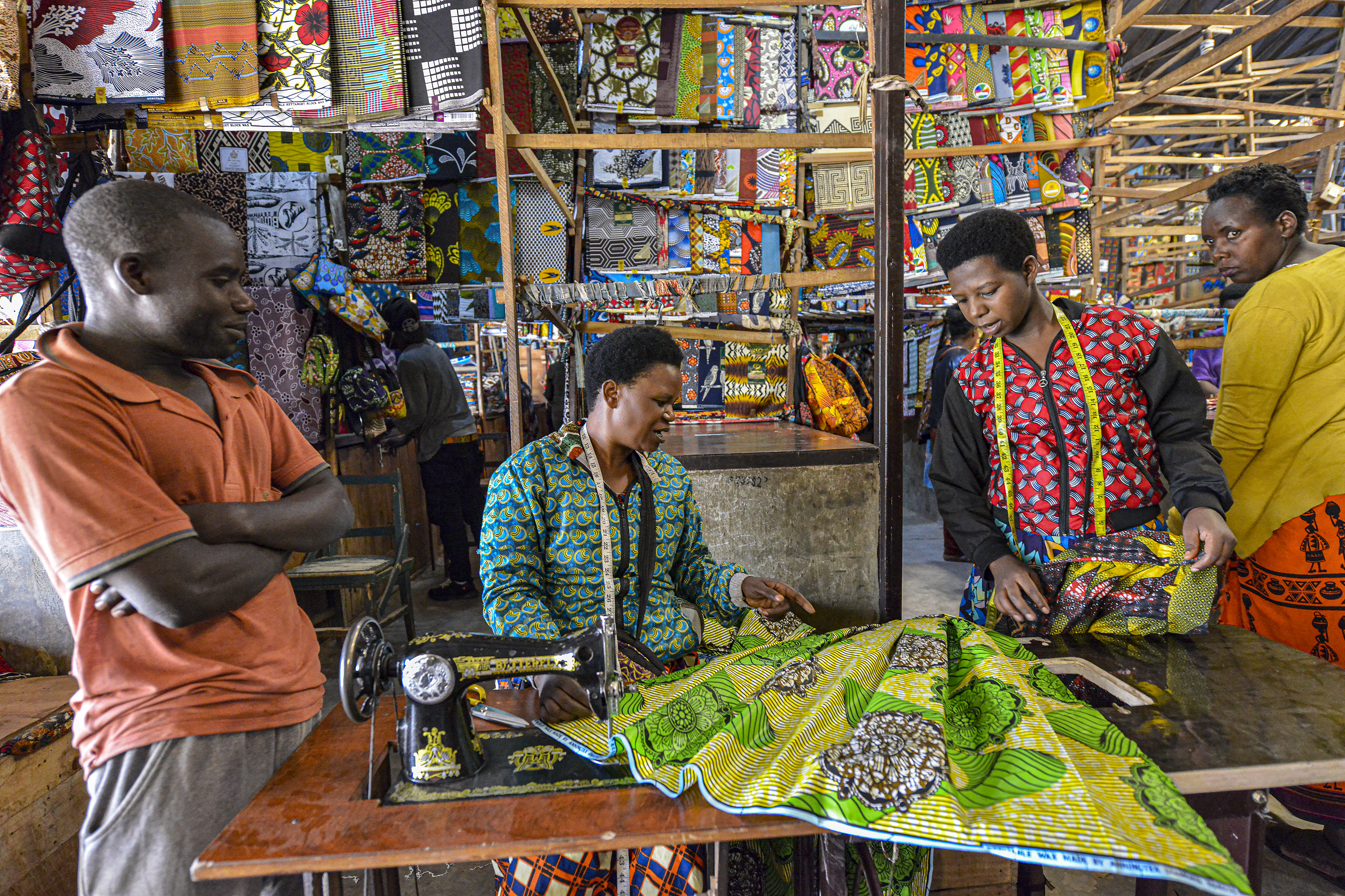 Tailors working with colorful Ankara fabric at a market stall in Kigali, Rwanda