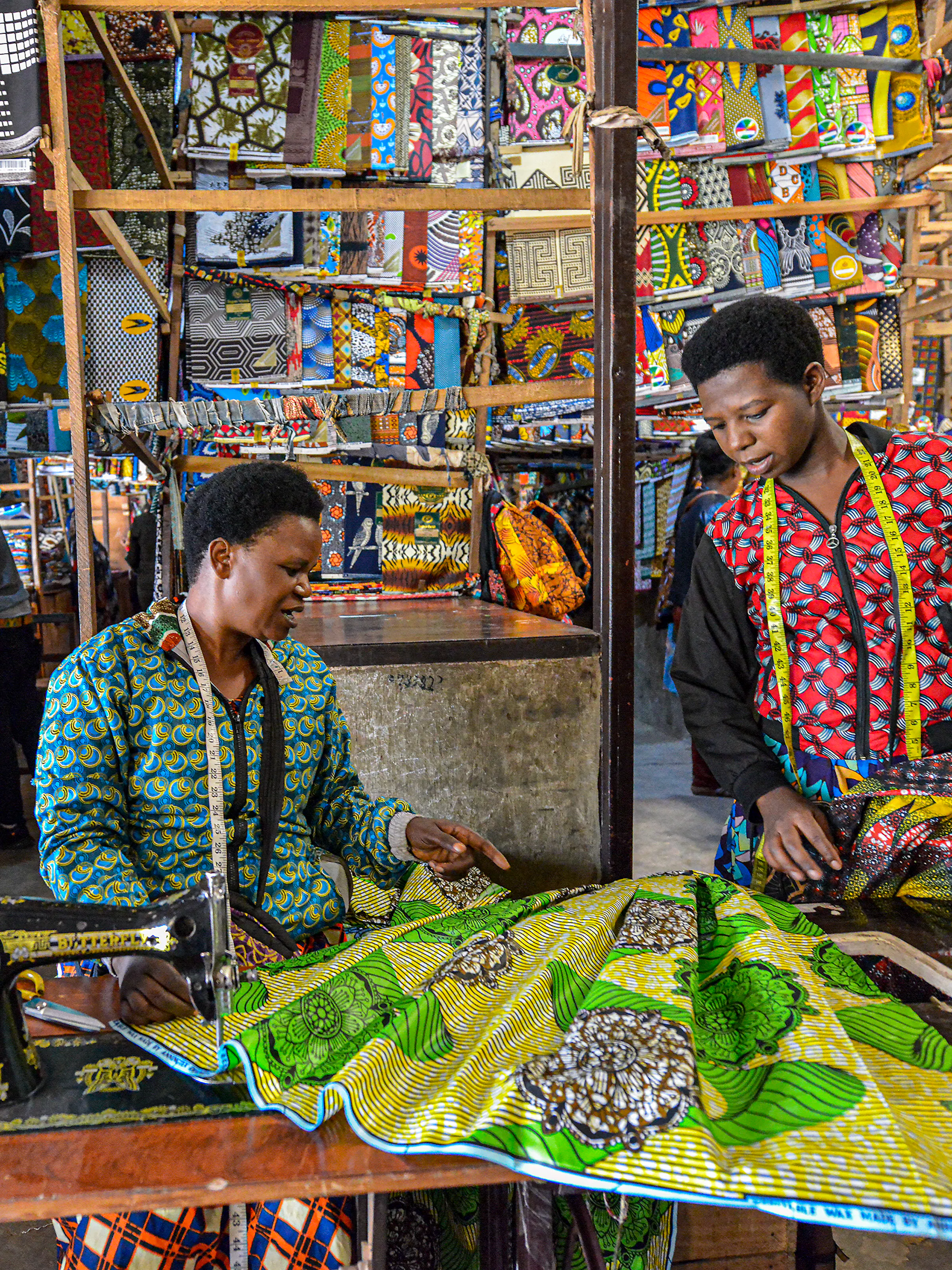 Tailors working with colorful Ankara fabric at a market stall in Kigali, Rwanda