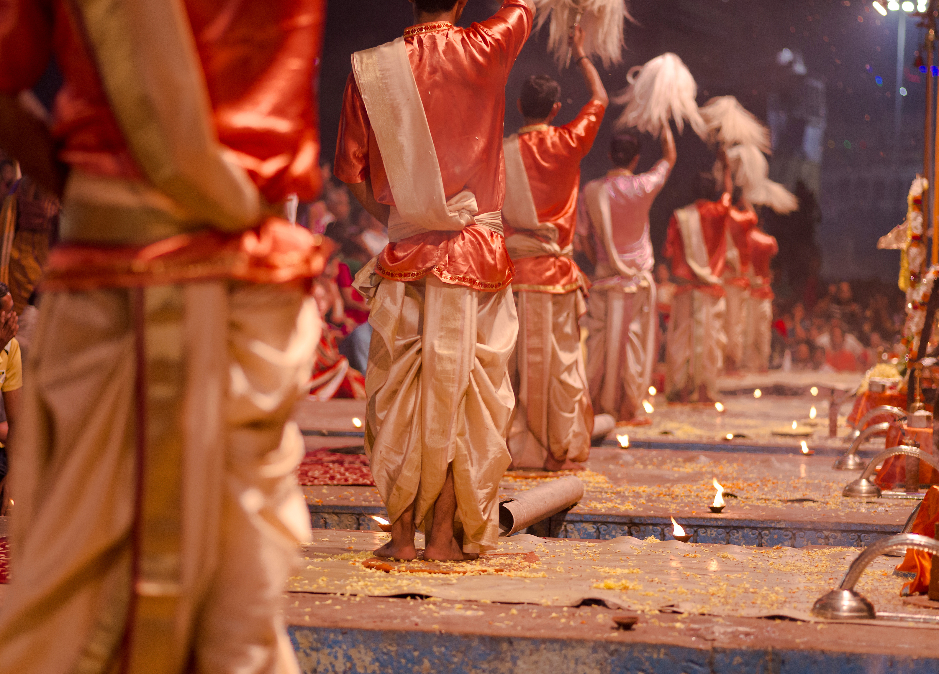 Traditional Ganga Aarti fire ceremony performers in orange and gold robes on the ghats of Varanasi, India
