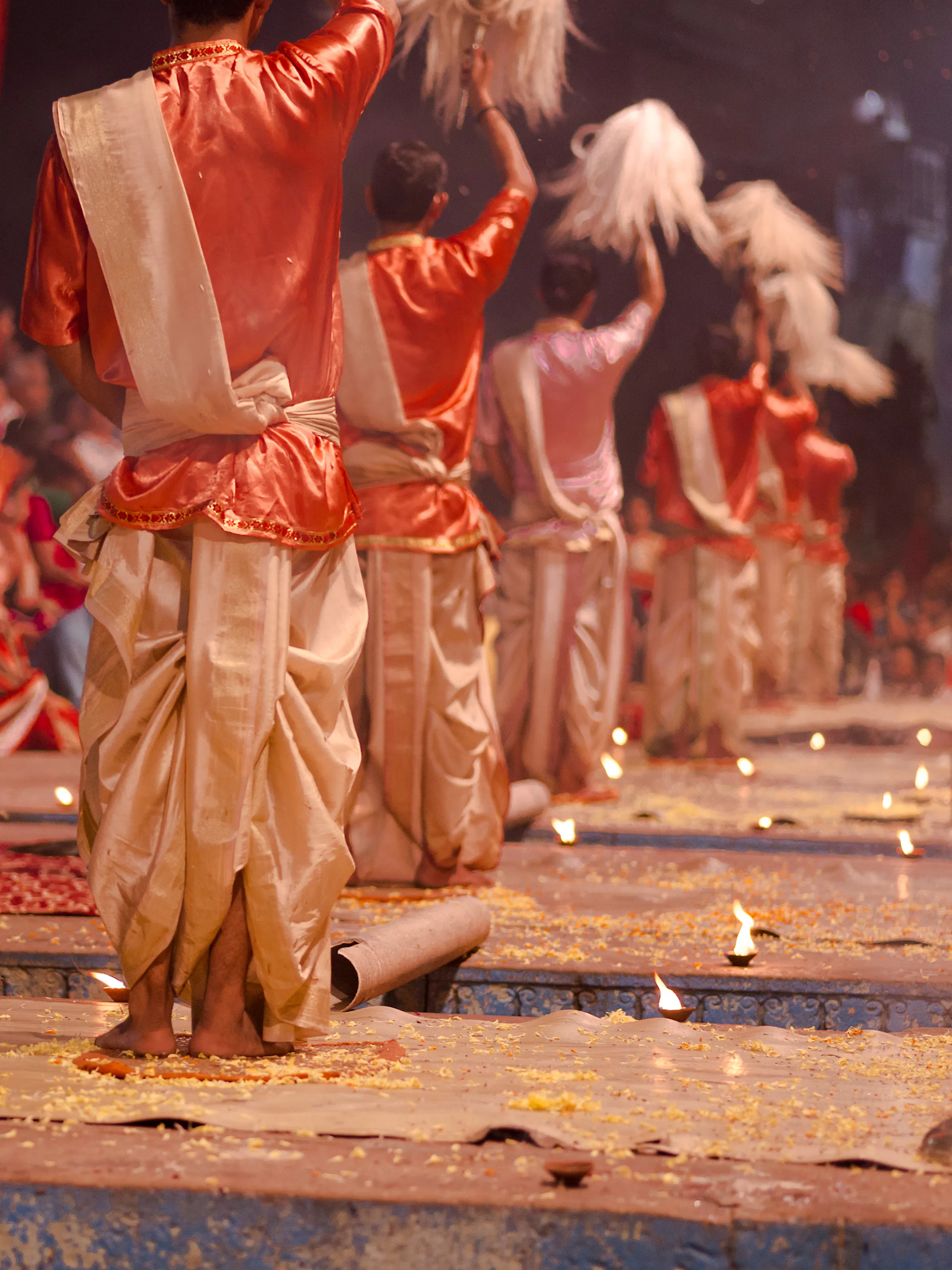 Traditional Ganga Aarti fire ceremony performers in orange and gold robes on the ghats of Varanasi, India