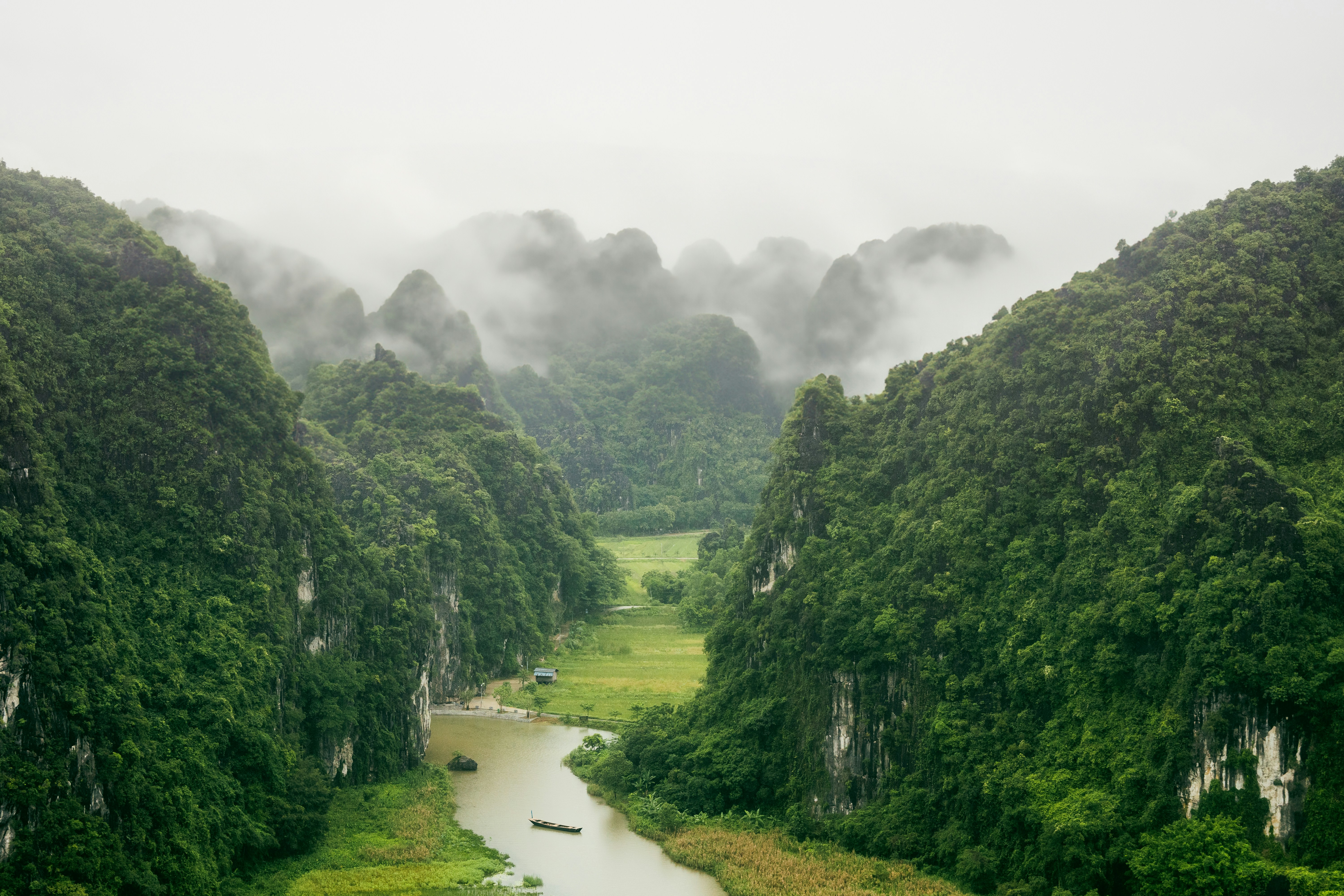 Traditional junk boat sailing among limestone islands, Ninh Binh Vietnam