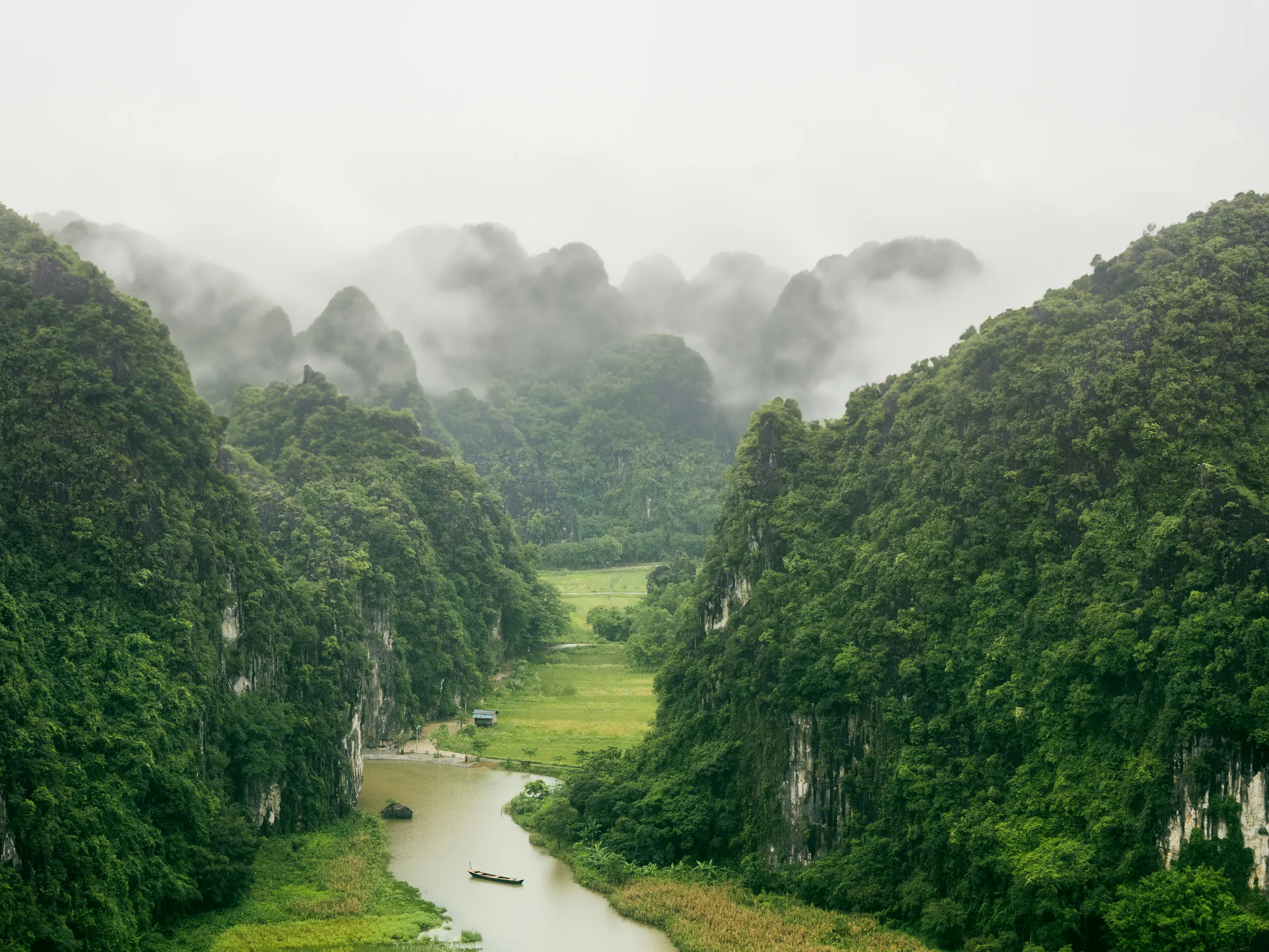 Traditional junk boat sailing among limestone islands, Ninh Binh Vietnam