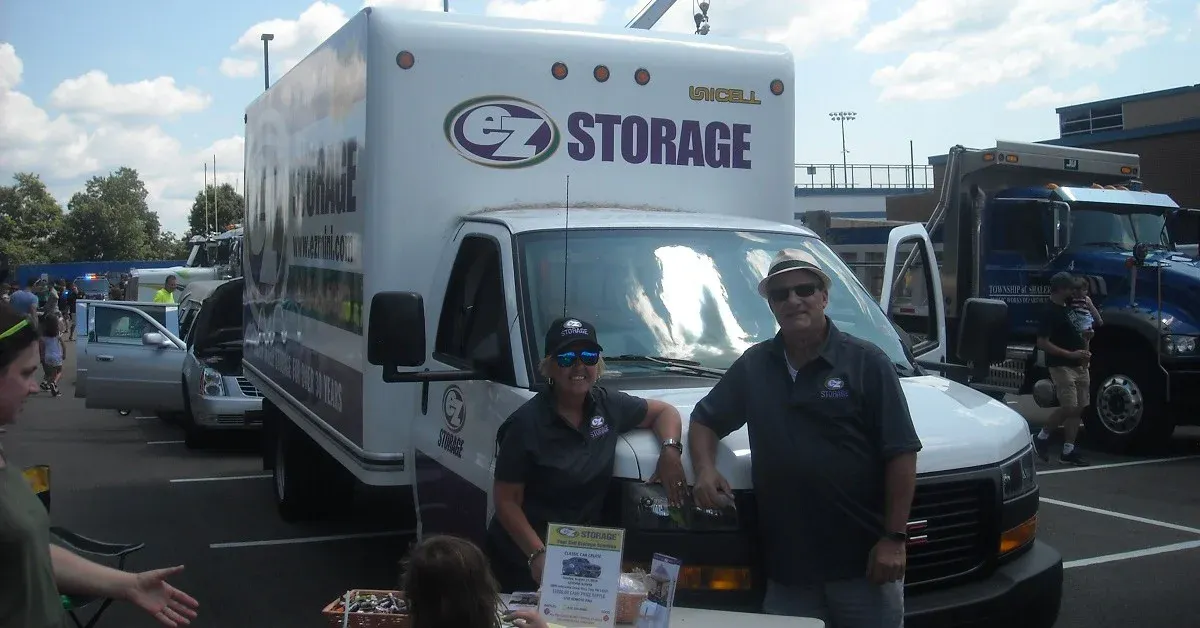 Frontal view of an EZ Storage moving truck with people facing camera & smiling