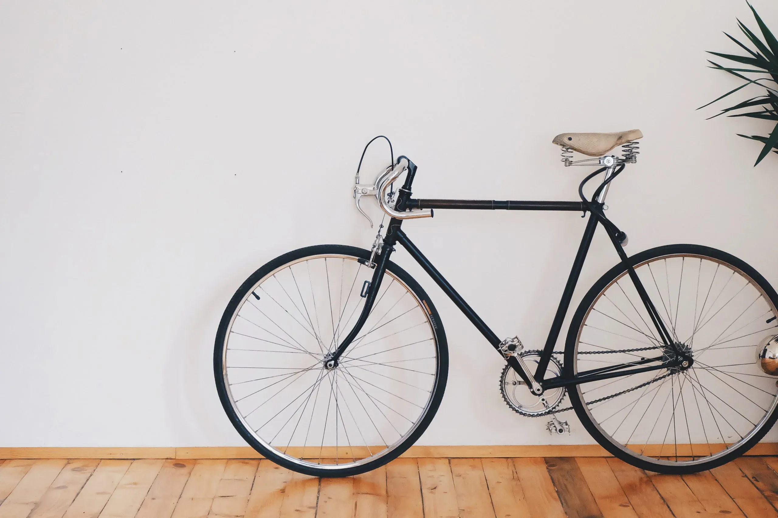 black bicycle standing up on white wall
