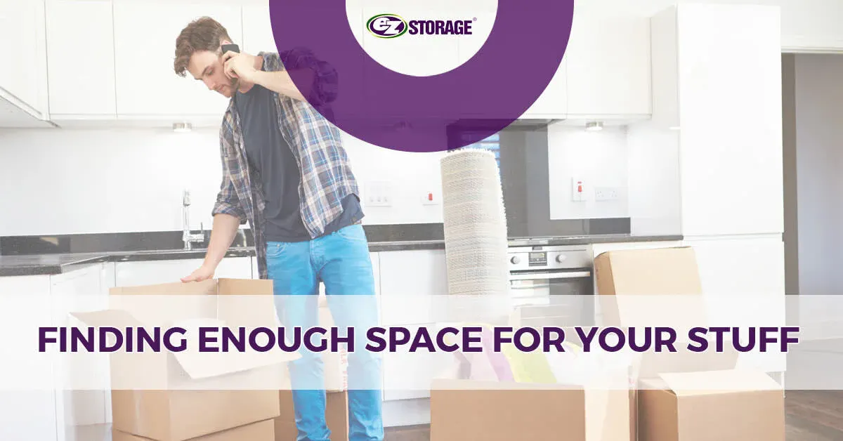 Man on phone in an empty kitchen with open moving boxes on the ground around him