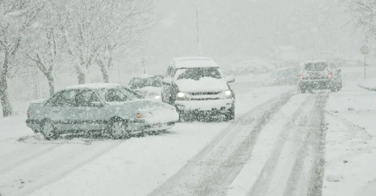 Four passenger vehicles on the road during a hazardous snow storm.