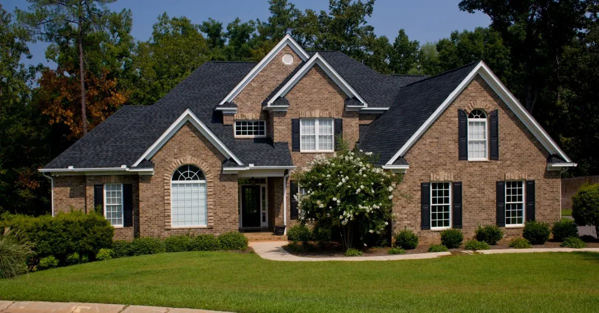 Front view of a two-story residential home with gables, manicured green lawn and driveway.