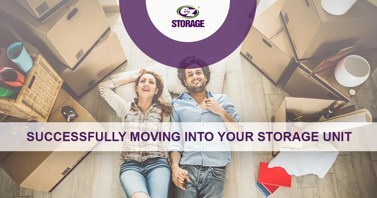 Couple laying down on the floor surrounded by boxes and text "Successfully moving into your storage unit"