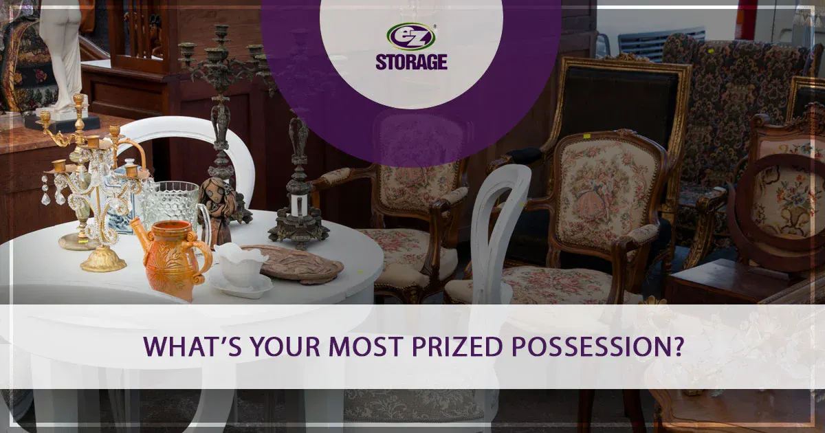 Antique chairs around white table with various antique table decor with EZ Storage logo and text "What's Your Most Prized Possession?"